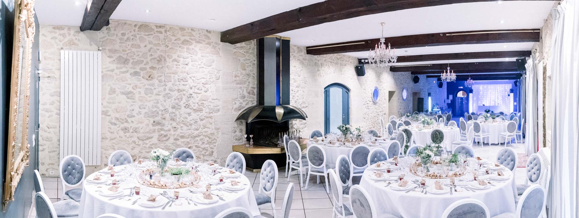 Salle de réception dressée de tables rondes sous les poutres apparentes