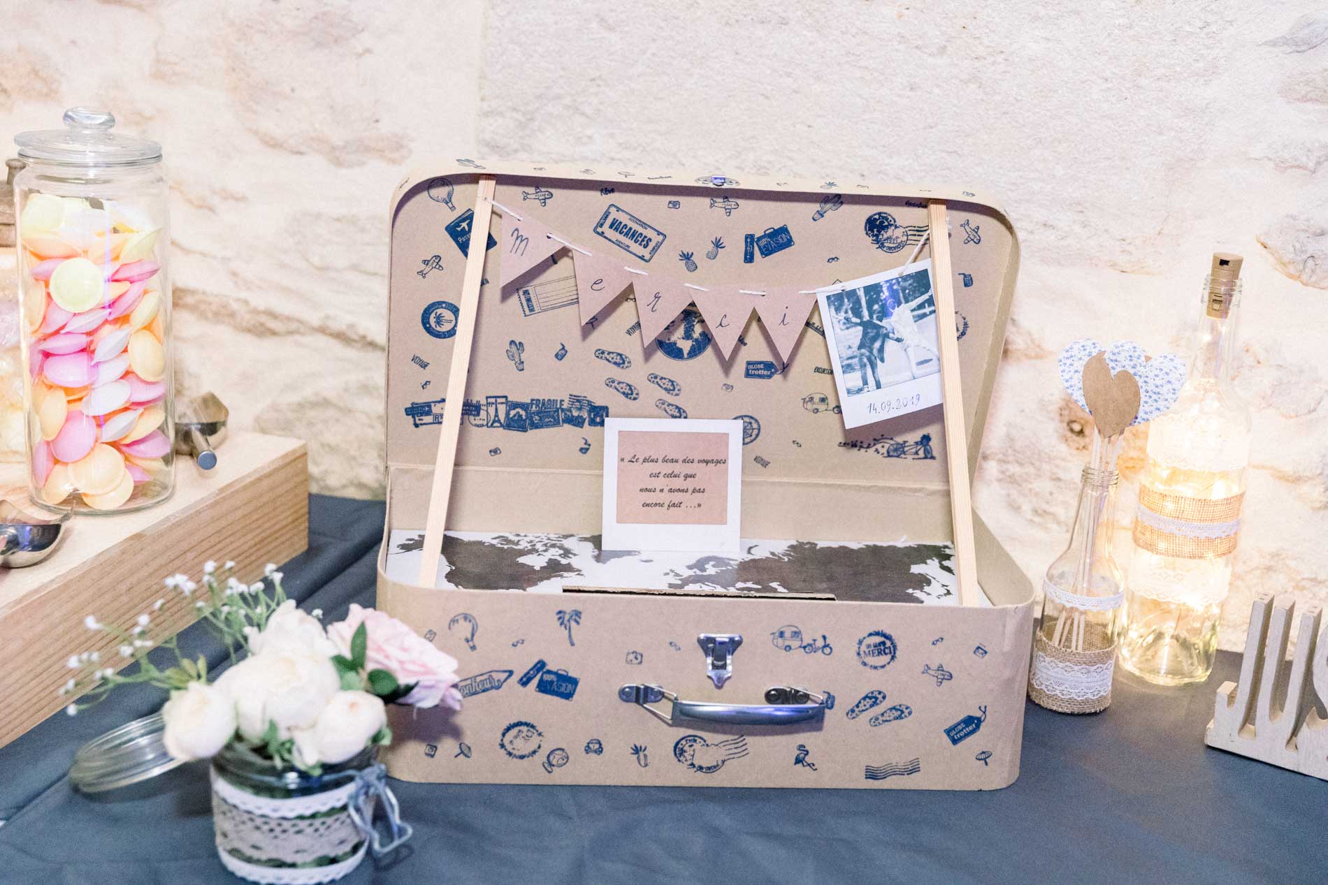 Valise vintage servant d'urne entourée de bonbonnières et de fleurs
