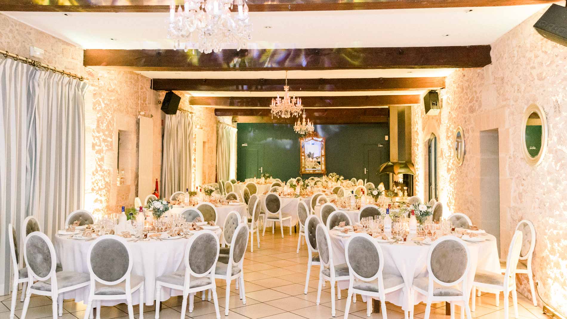 Salle de réception du Domaine de Valmont prête pour le dîner, lustres allumés