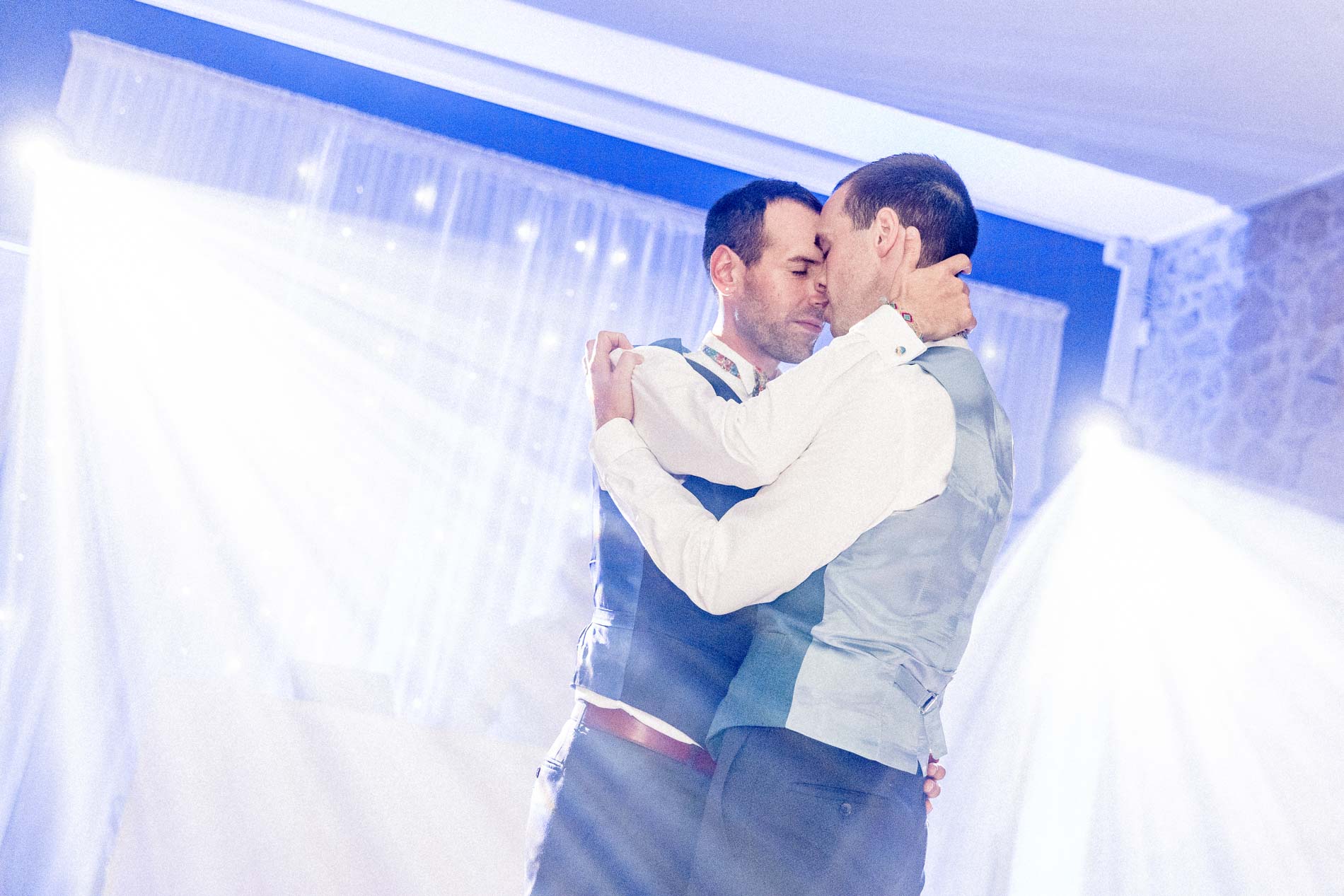 Baiser des mariés pendant la première danse, lumières et fumée