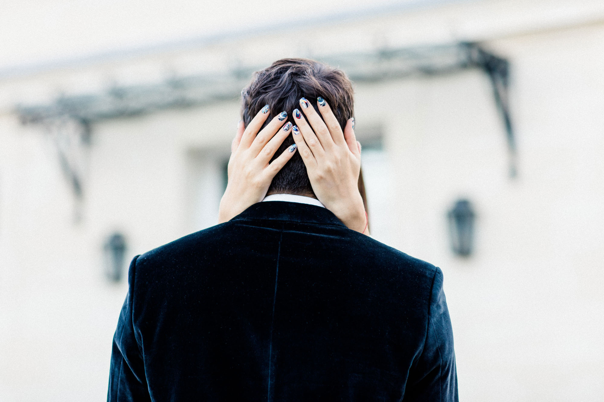 She covers her partner's eyes with her hands, seen from behind