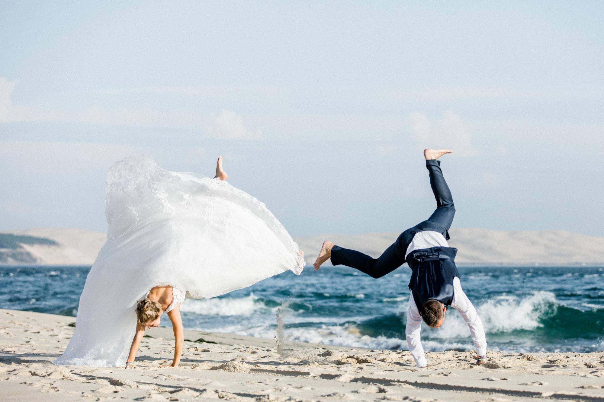 Les mariés font la roue sur la plage pendant la séance trash the dress
