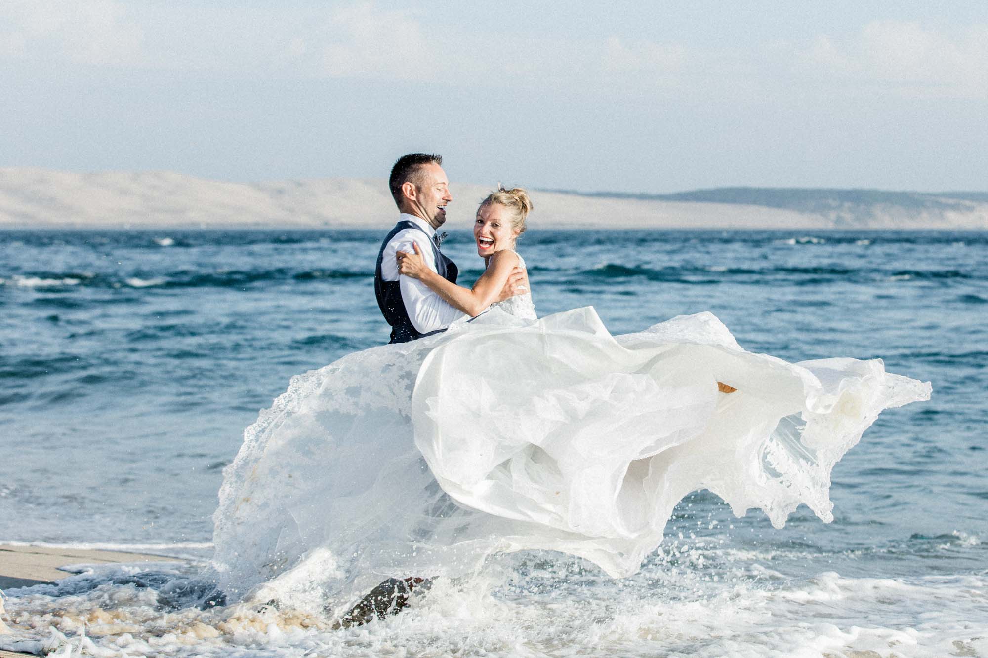 Groom carrying the bride through the waves, trash the dress shoot at Cap Ferret