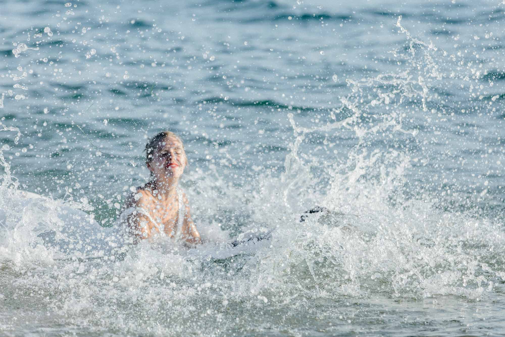 La mariée plonge dans une gerbe d'eau pendant la séance trash the dress