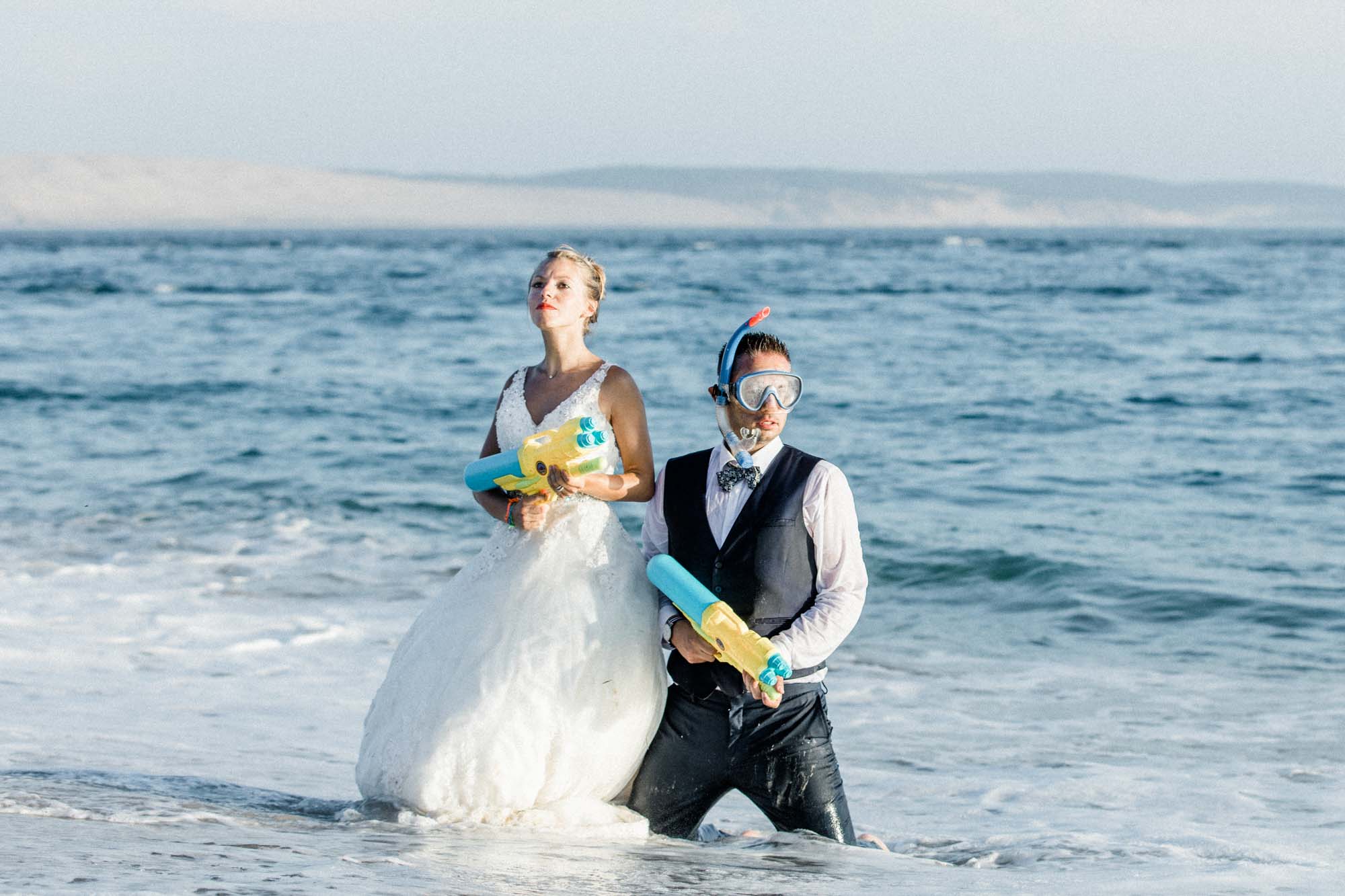 Les mariés en masque de plongée et pistolets à eau dans l'océan