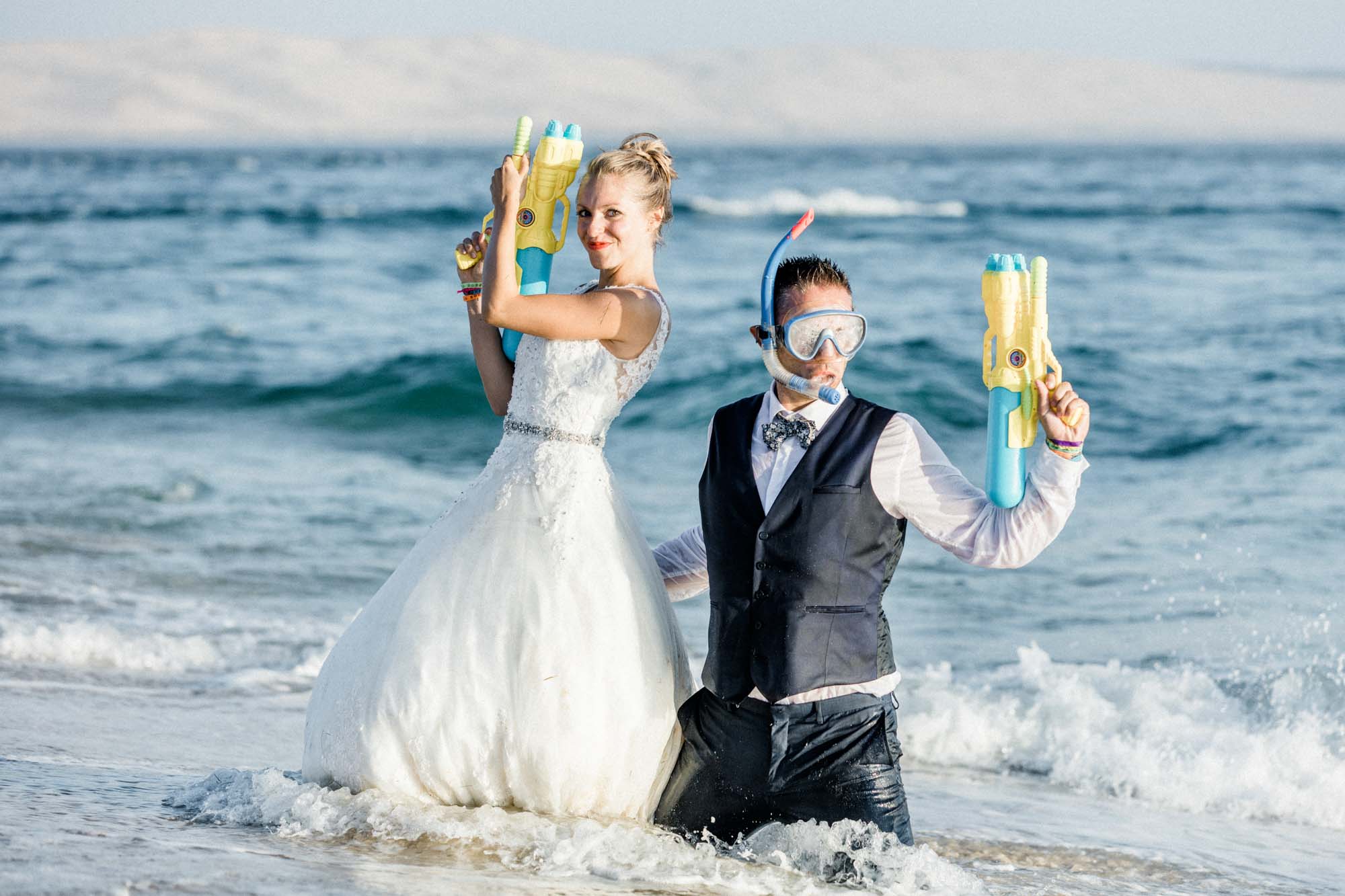 La mariée brandit un pistolet à eau, le marié en tuba à ses côtés