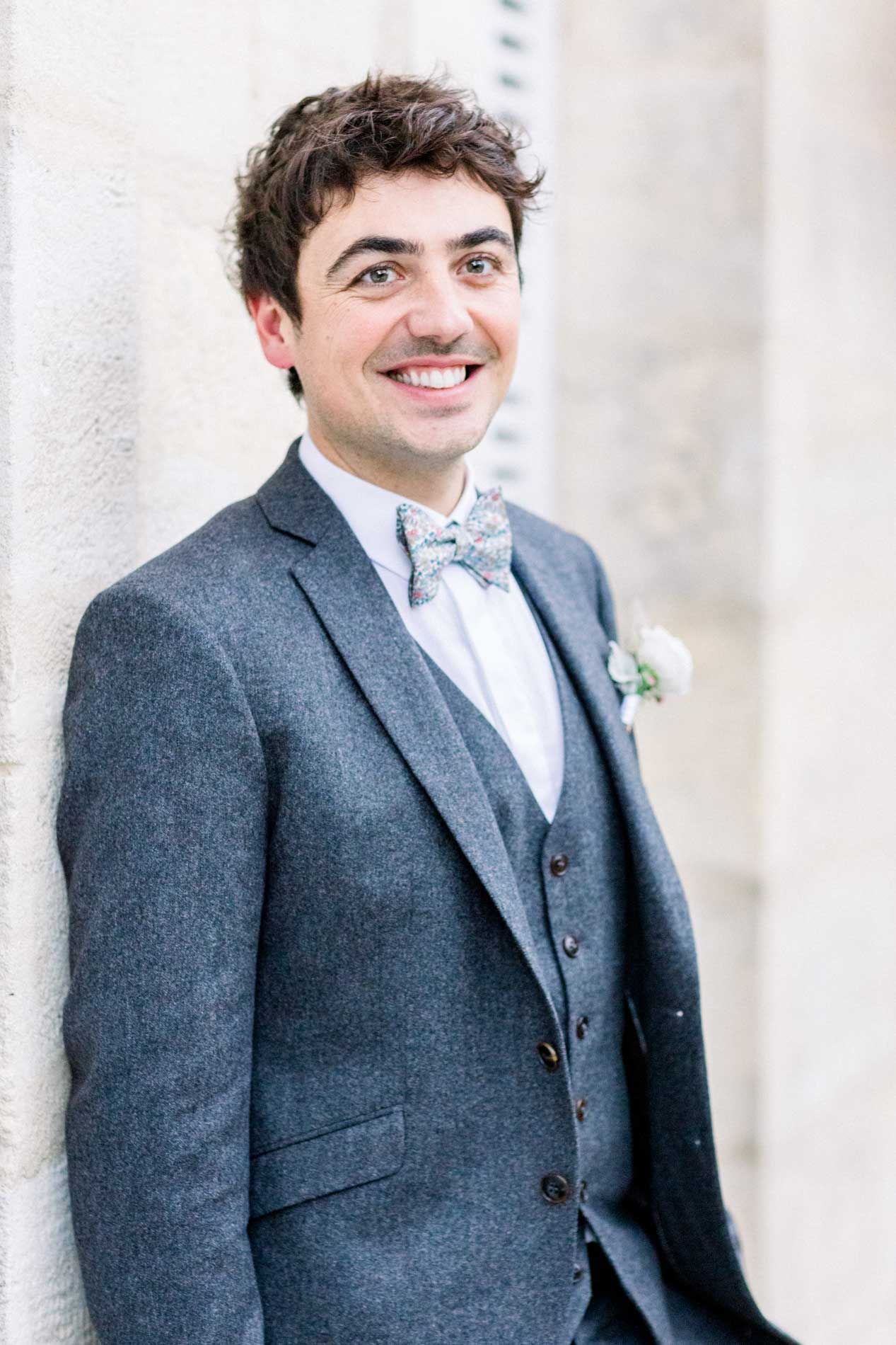 The groom in his Blandin et Delloye suit leaning against the stone wall