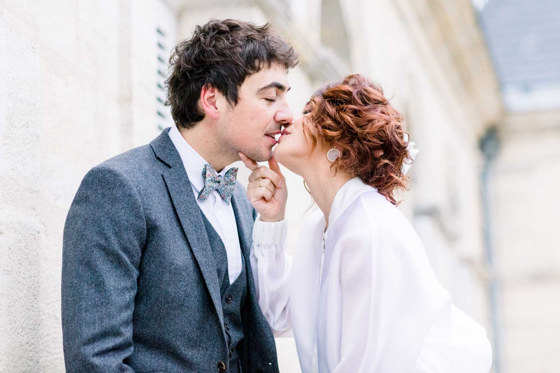 The bride and groom kissing in front of the Chartreuse's stone facade
