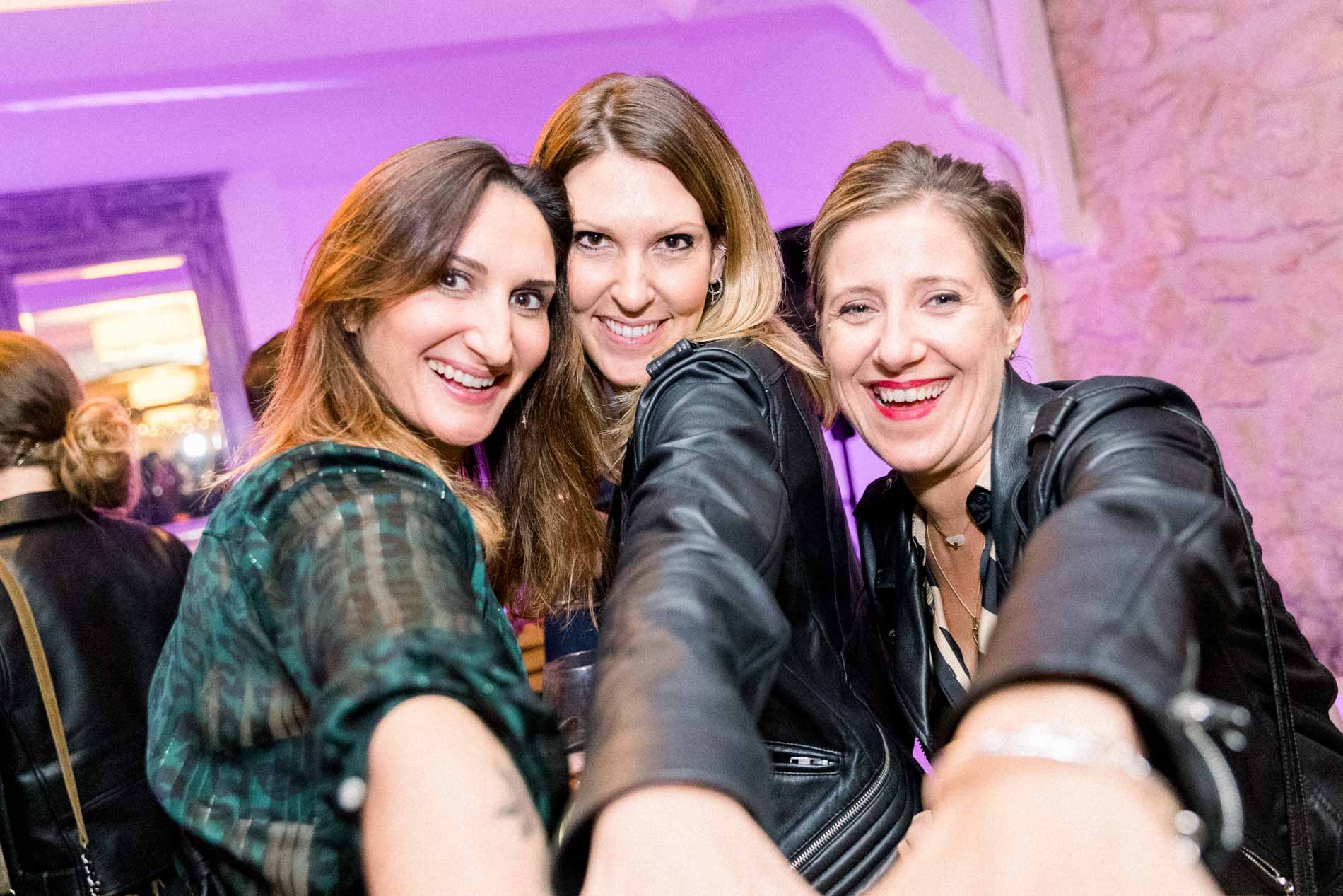 Three guests taking a selfie under the purple lights of the party