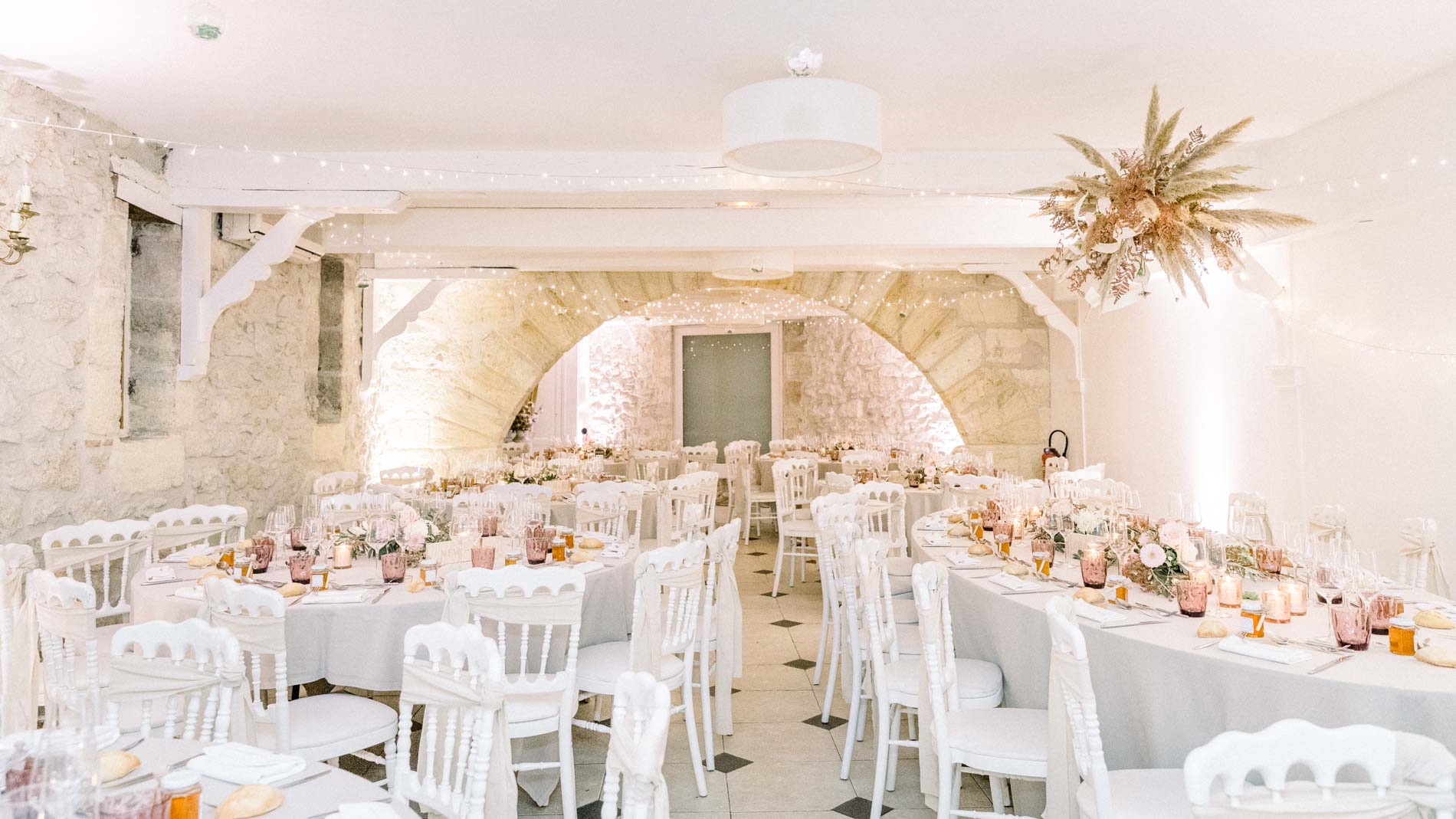 Vaulted stone reception room laid with white tables for dinner