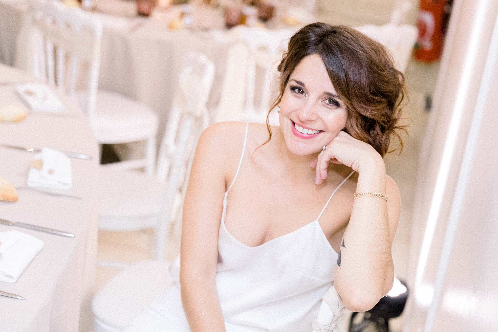 The smiling bride in a silk camisole, leaning back in the Chartreuse des Eyres reception room