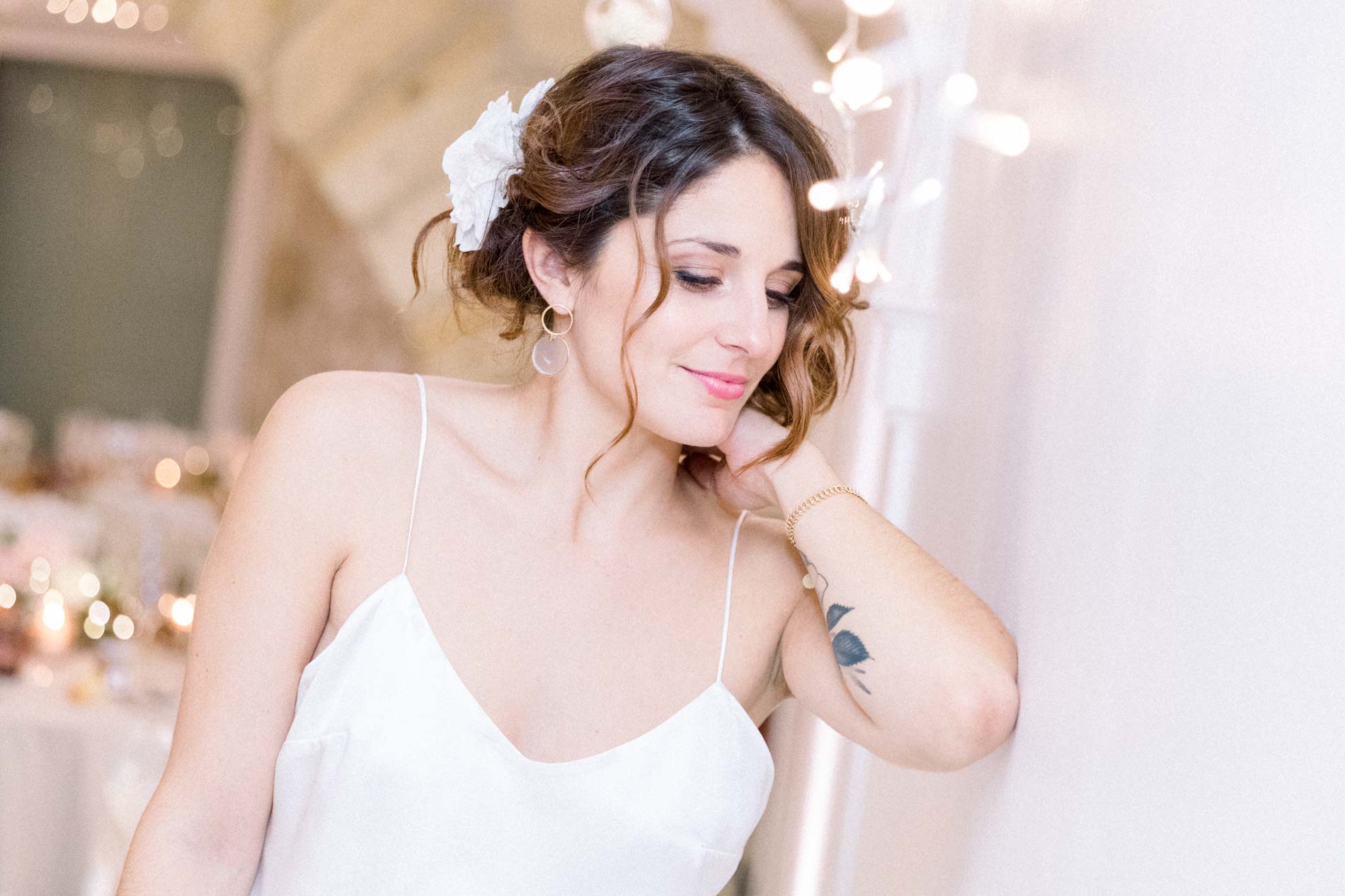 The bride in a silk camisole with a flower in her hair, looking down