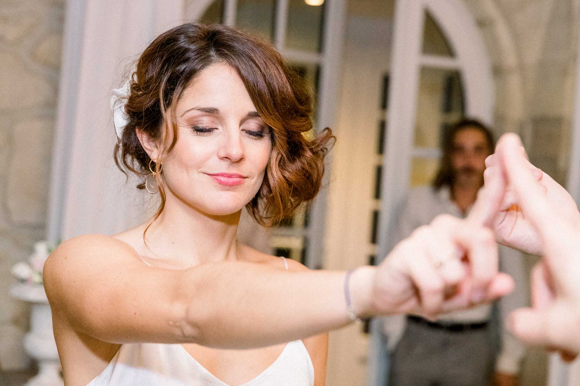 The bride, eyes closed, reaching out her hand during a guest game
