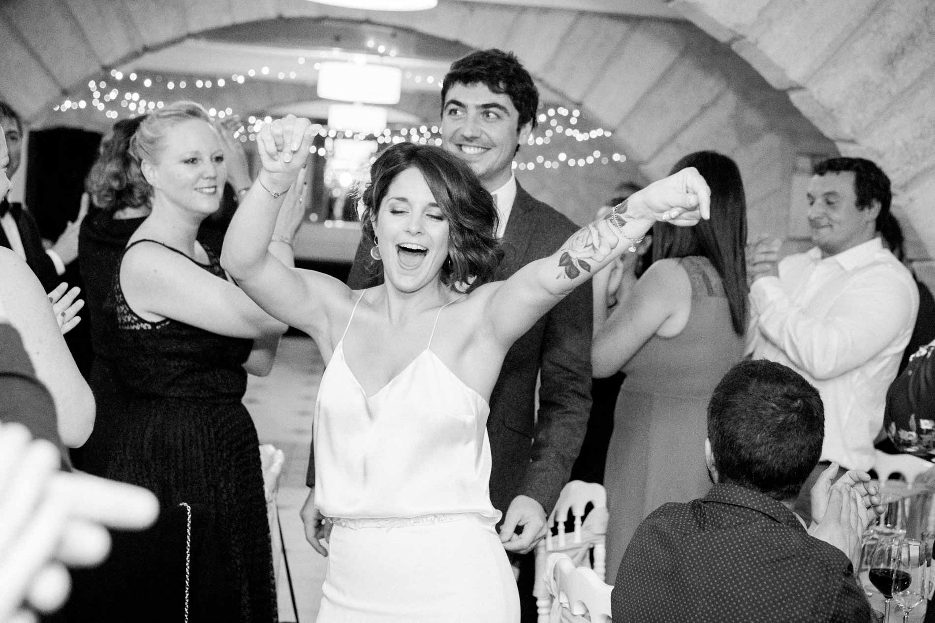The bride raising her arms as she enters the room, in black and white