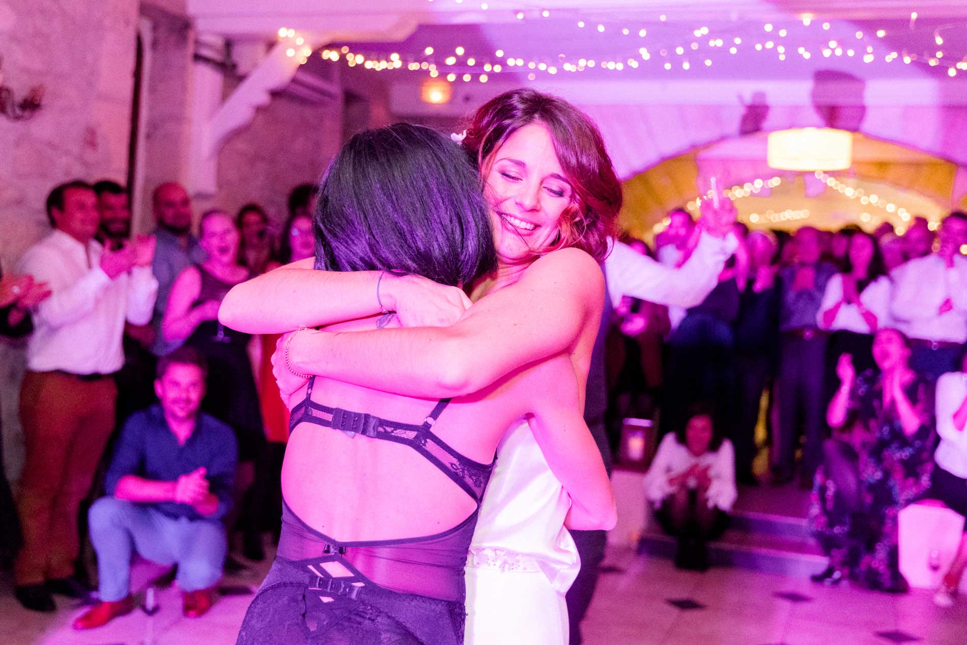 The cabaret dancer hugging the bride on the dance floor under pink lights