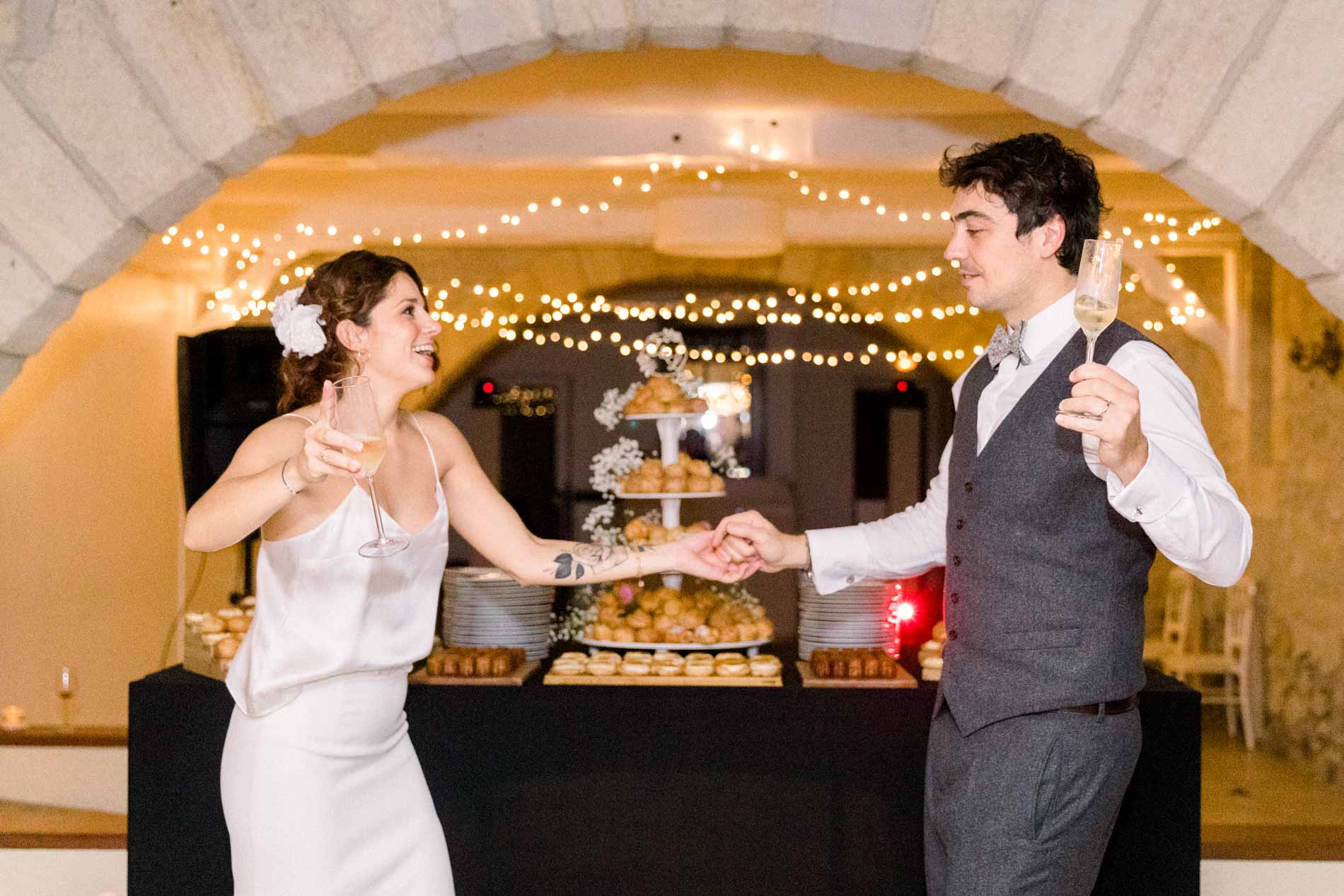 The bride and groom dancing in front of the dessert tower beneath the lit vault