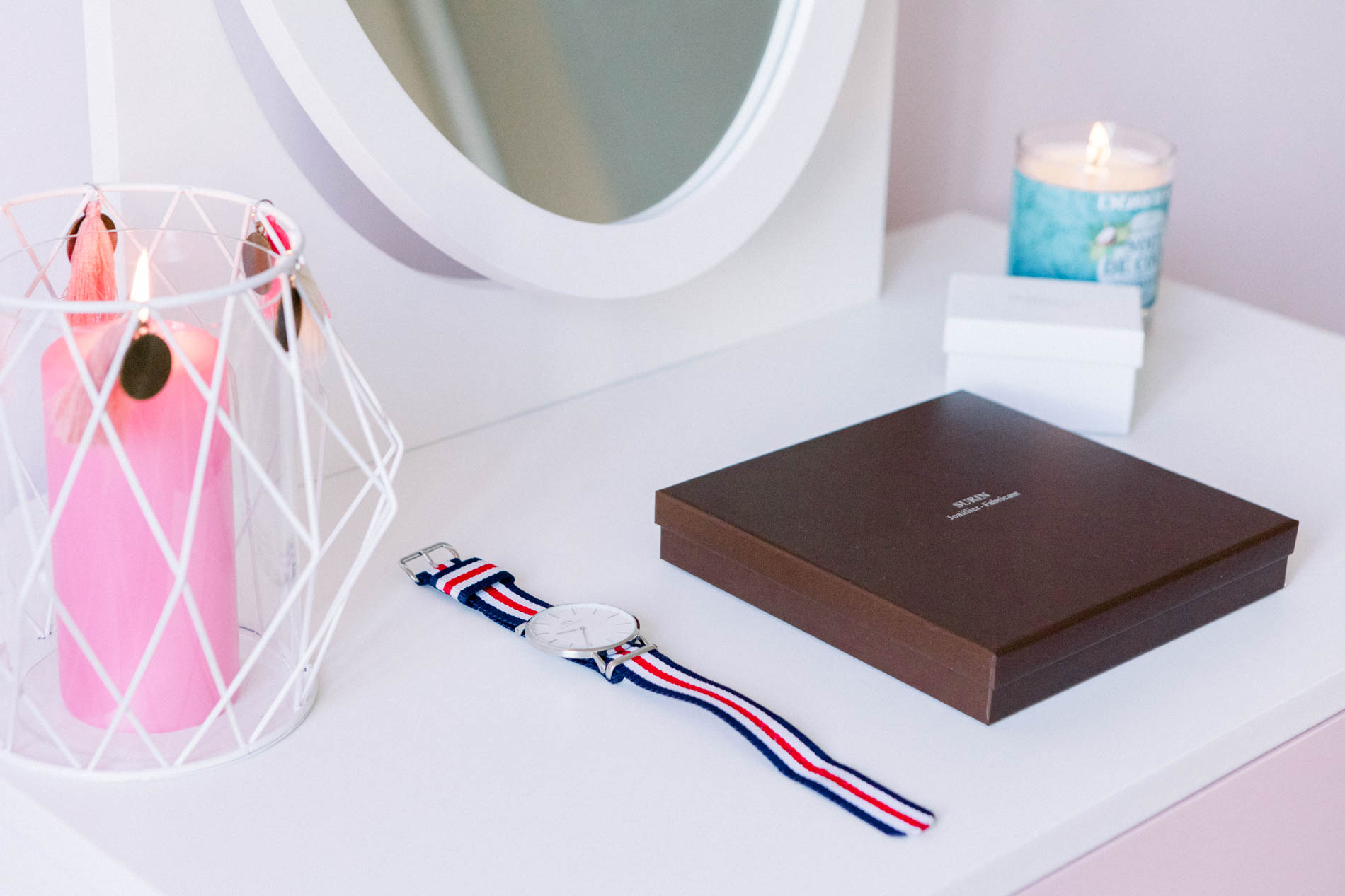 Watch, gift box and candles on a white dressing table during the wedding preparations