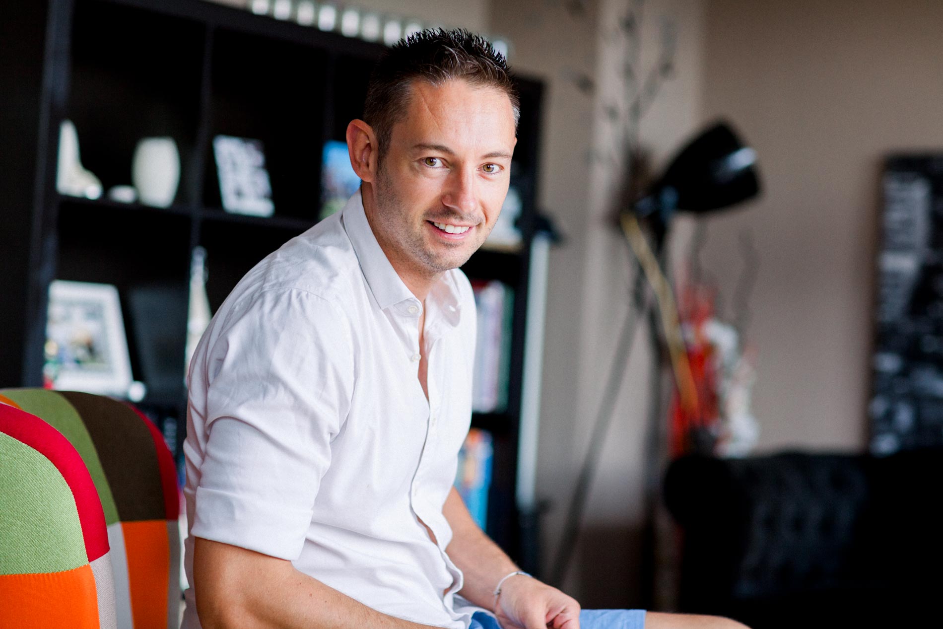 Smiling groom sitting in his living room while getting ready in Mérignac