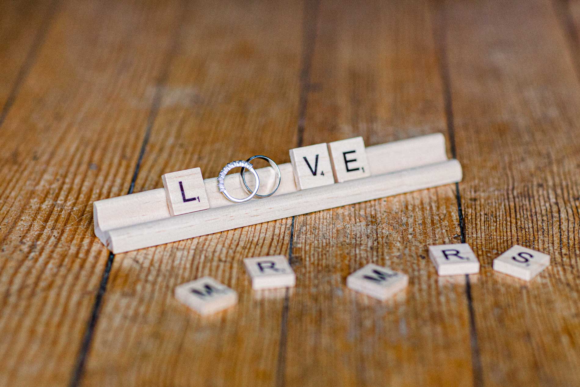 Scrabble tiles spelling LOVE and MR MRS with the wedding rings on wood