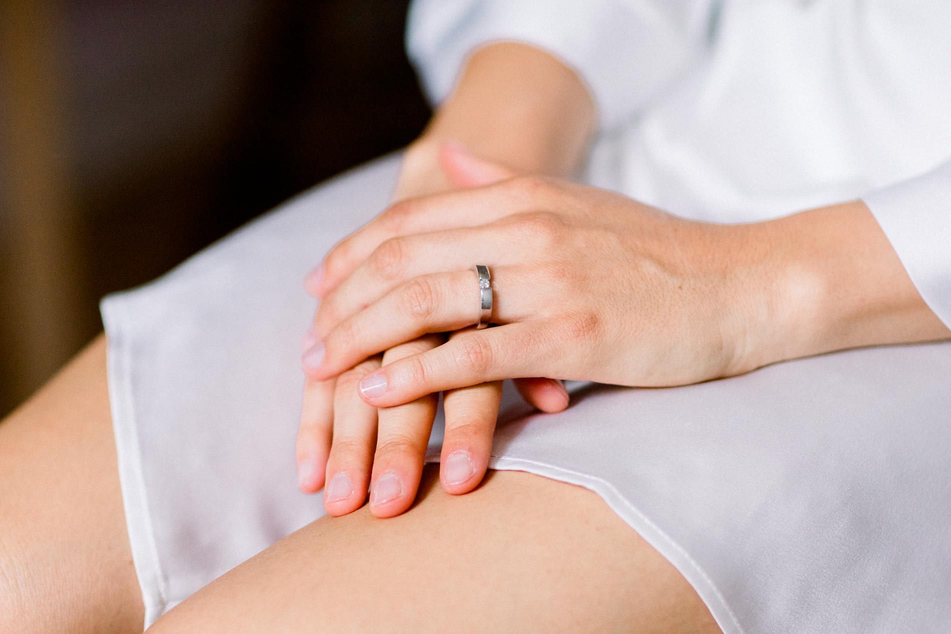 Bride's hands resting on her lap, engagement ring on her finger