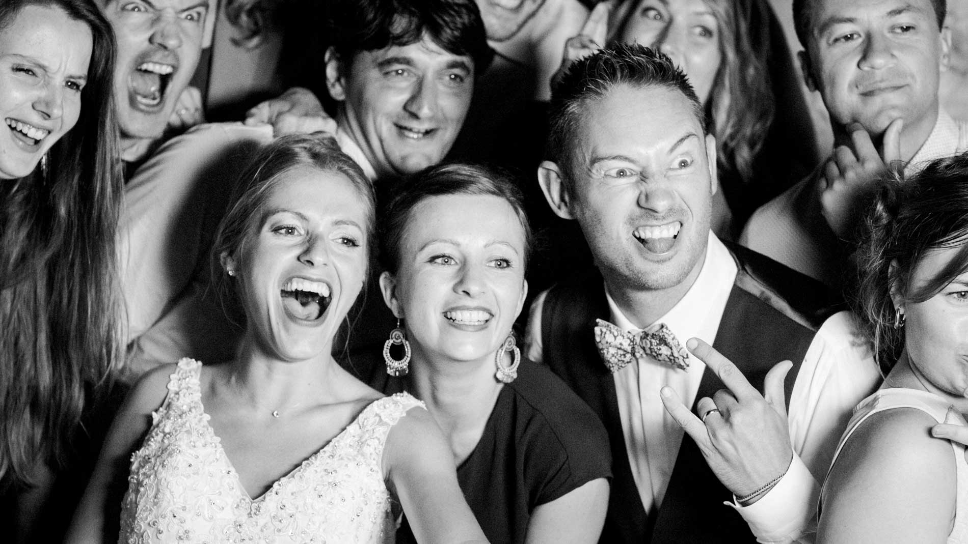 Bride and guests laughing at the photo booth during the evening, in black and white