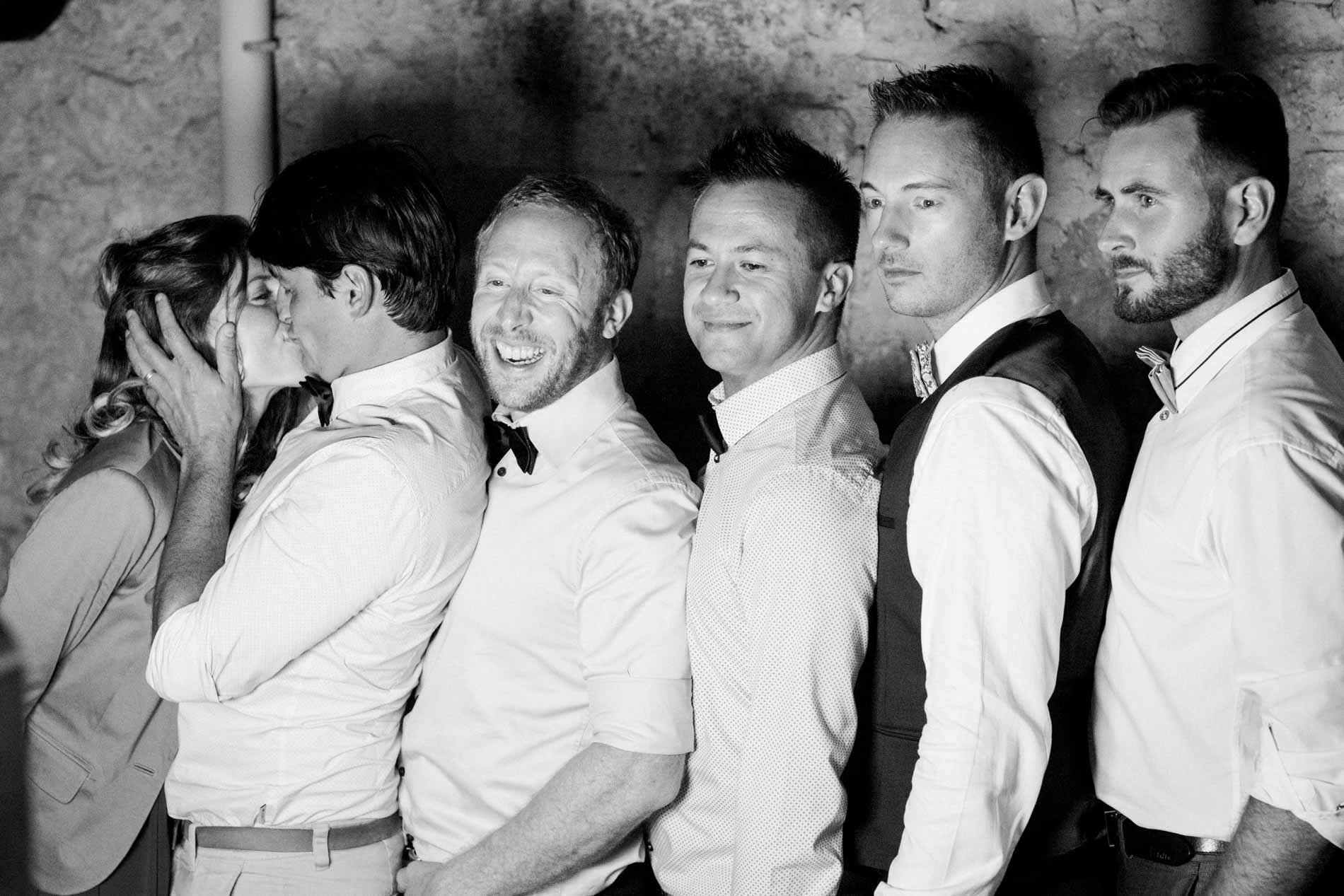 Groom and his friends pulling faces at the photo booth, in black and white