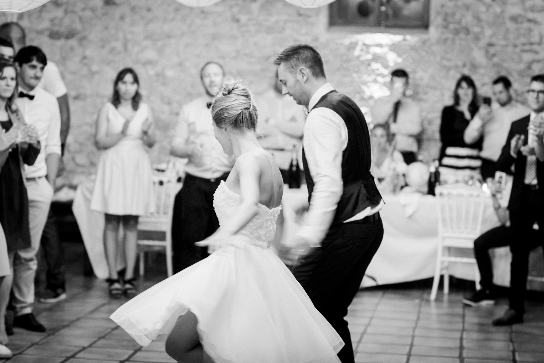 Bride and groom dancing in front of their guests, in black and white