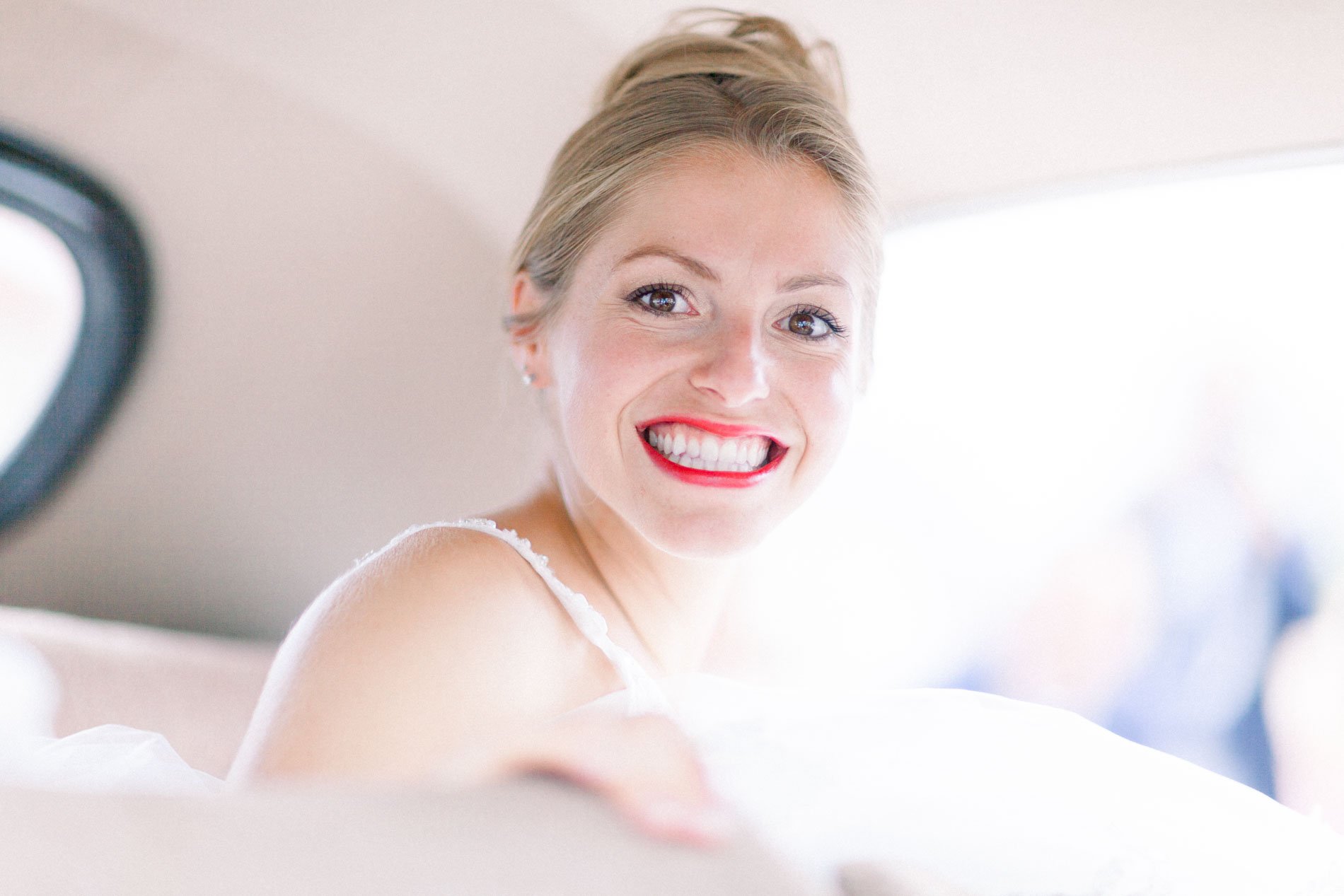 Smiling bride in the back seat of the wedding car in Mérignac