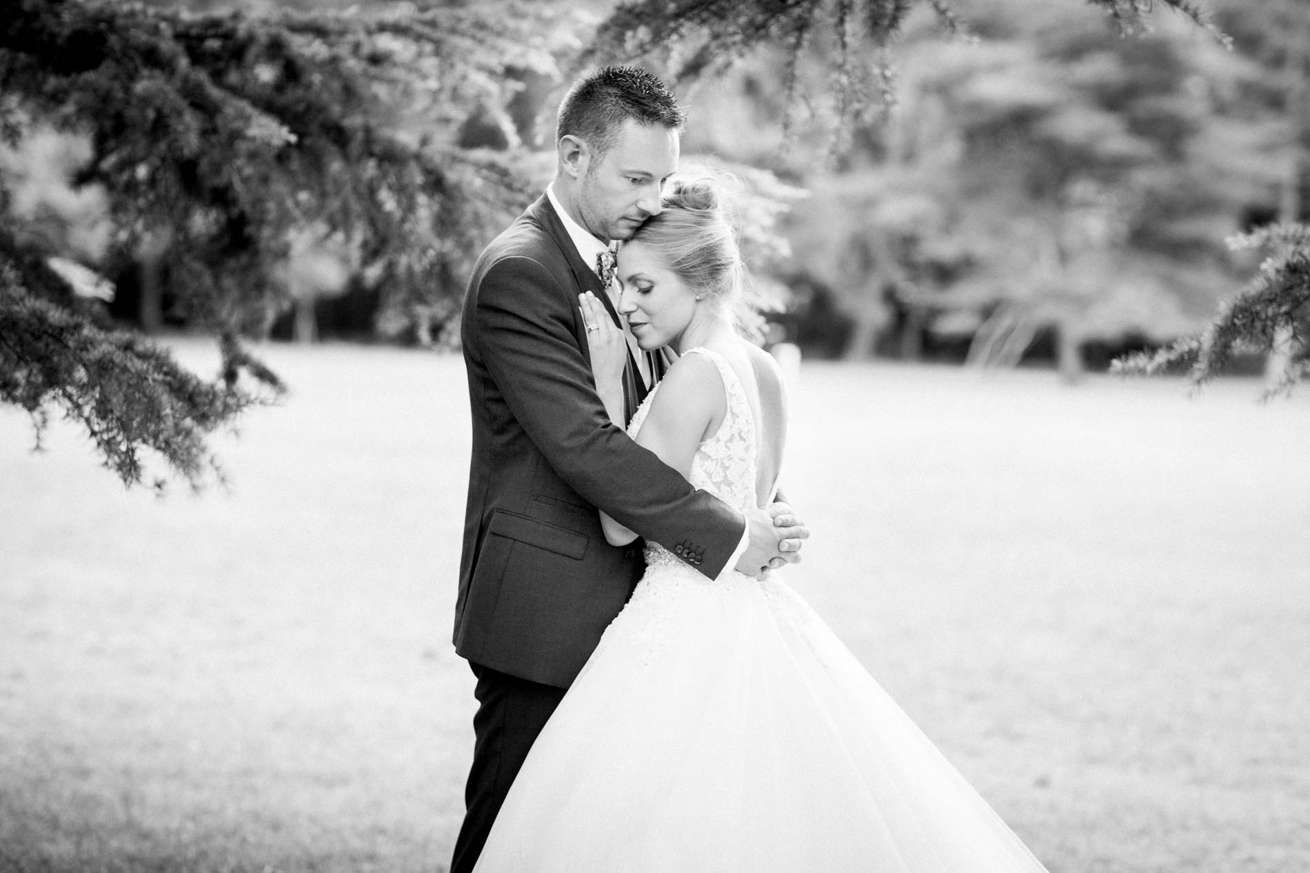 Bride and groom embracing beneath a cedar at Château de Cujac, black and white