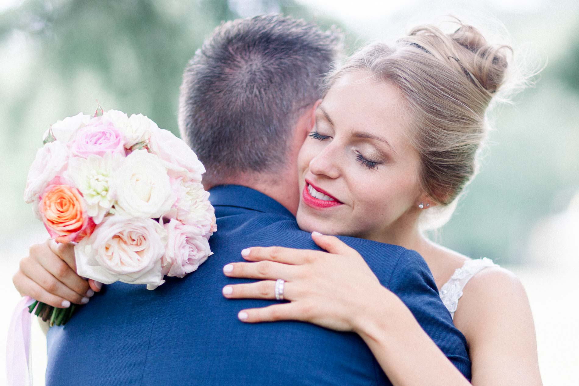 Bride smiling over the groom's shoulder, bouquet in hand