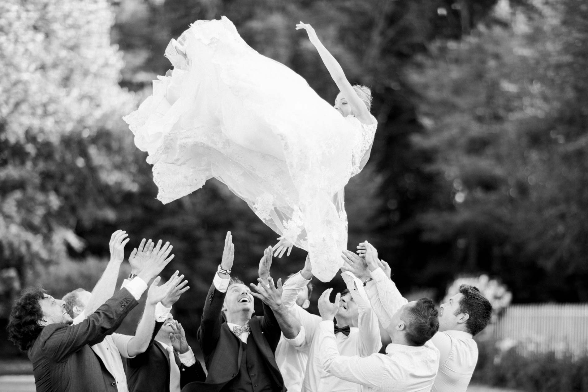 Bride tossed into the air by the guests, in black and white
