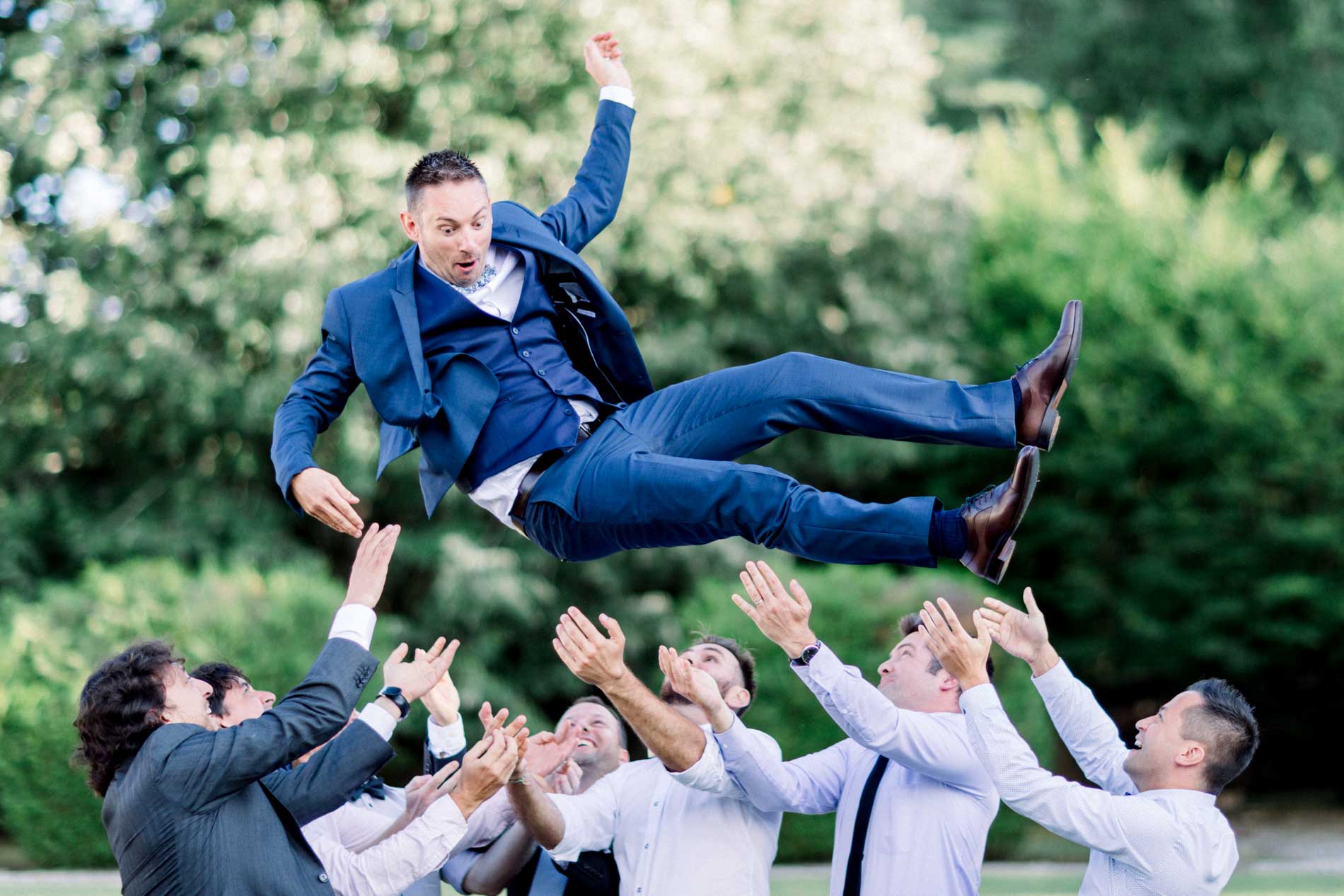 Groom thrown into the air by his friends on the château lawn
