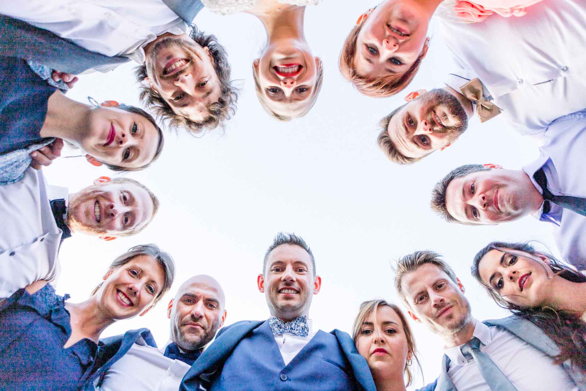Low-angle group photo of guests leaning in a circle over the camera