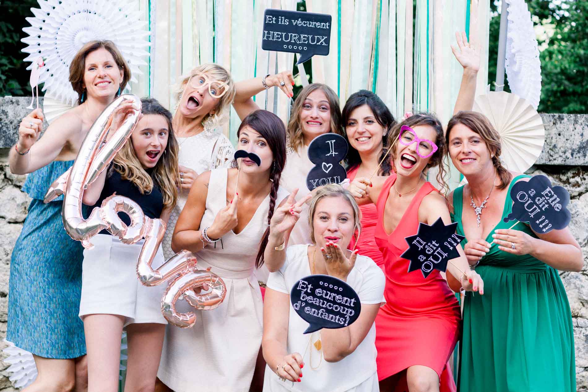 Female guests posing with photo booth props and a love balloon