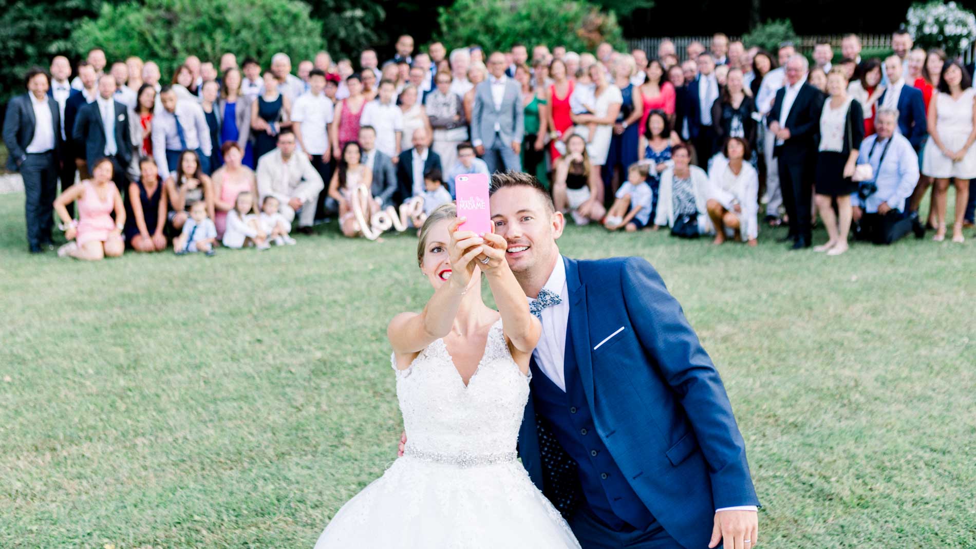 Bride and groom toasting in front of all their guests gathered for the group photo