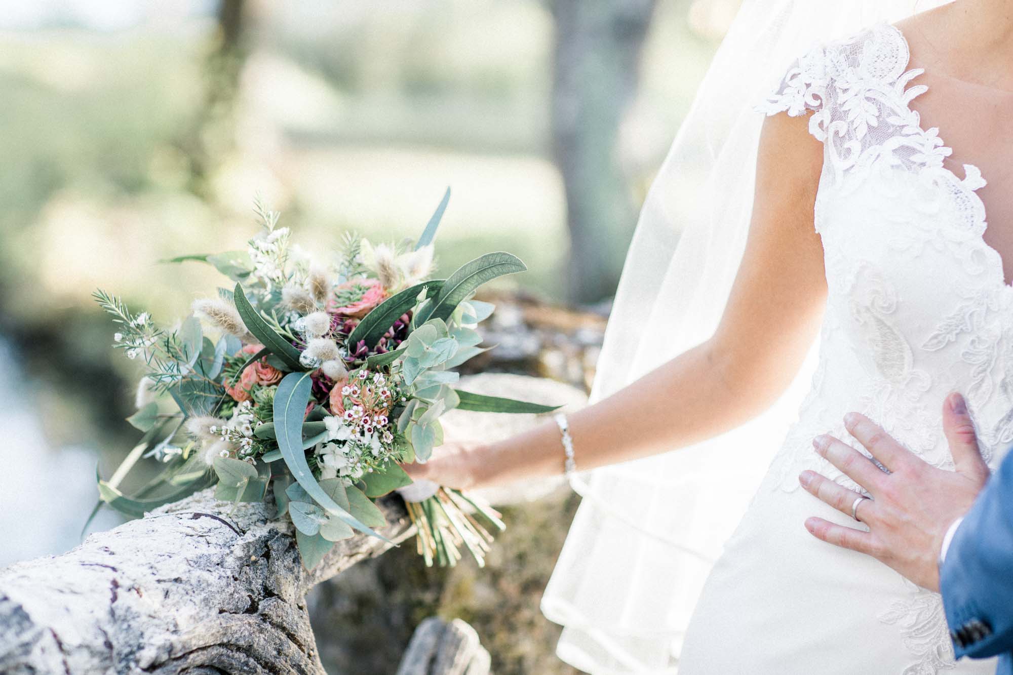 Country-style bouquet and the groom's hand on the bride's waist