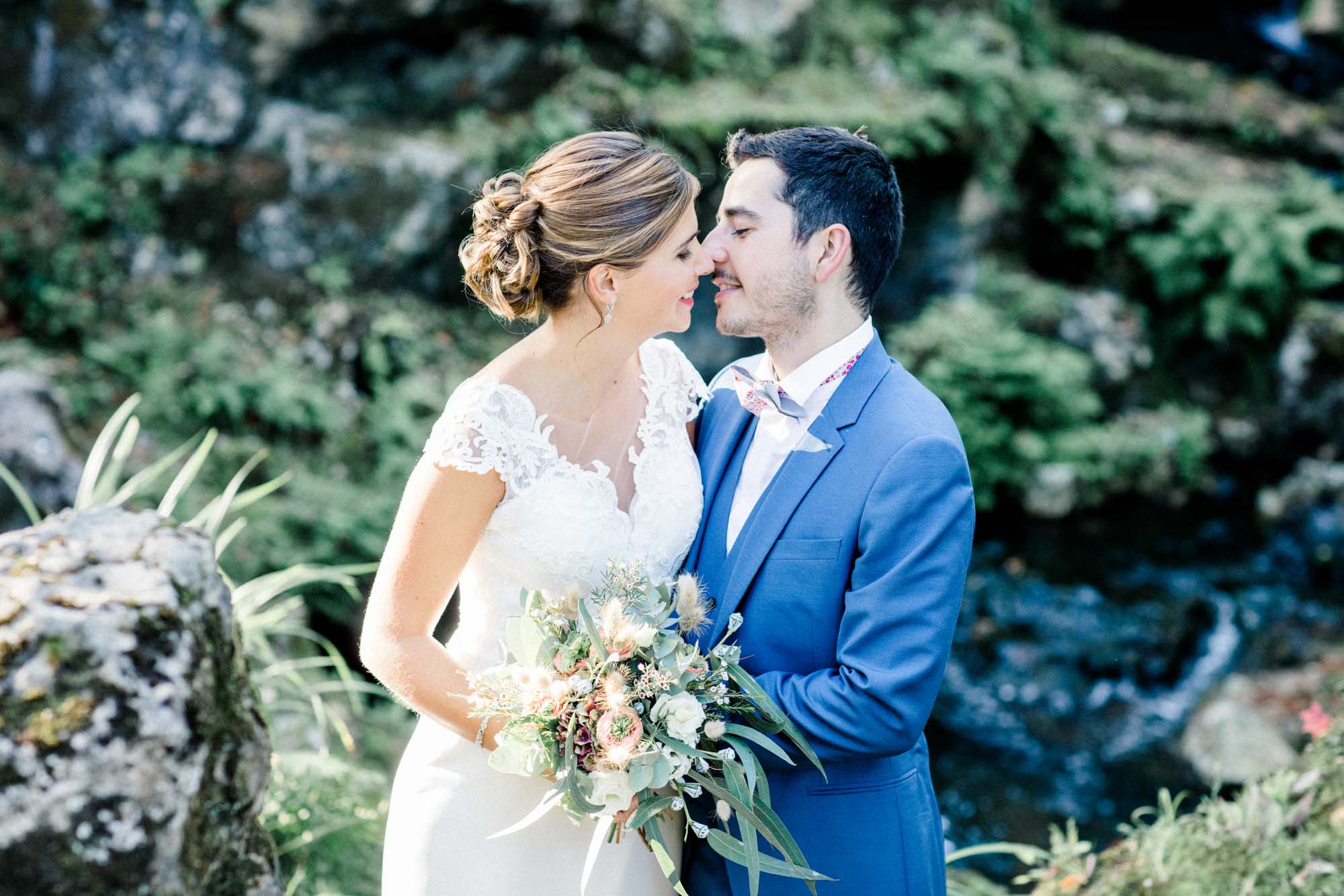 Couple nose to nose in front of the rocks and waterfall in Parc de Majolan