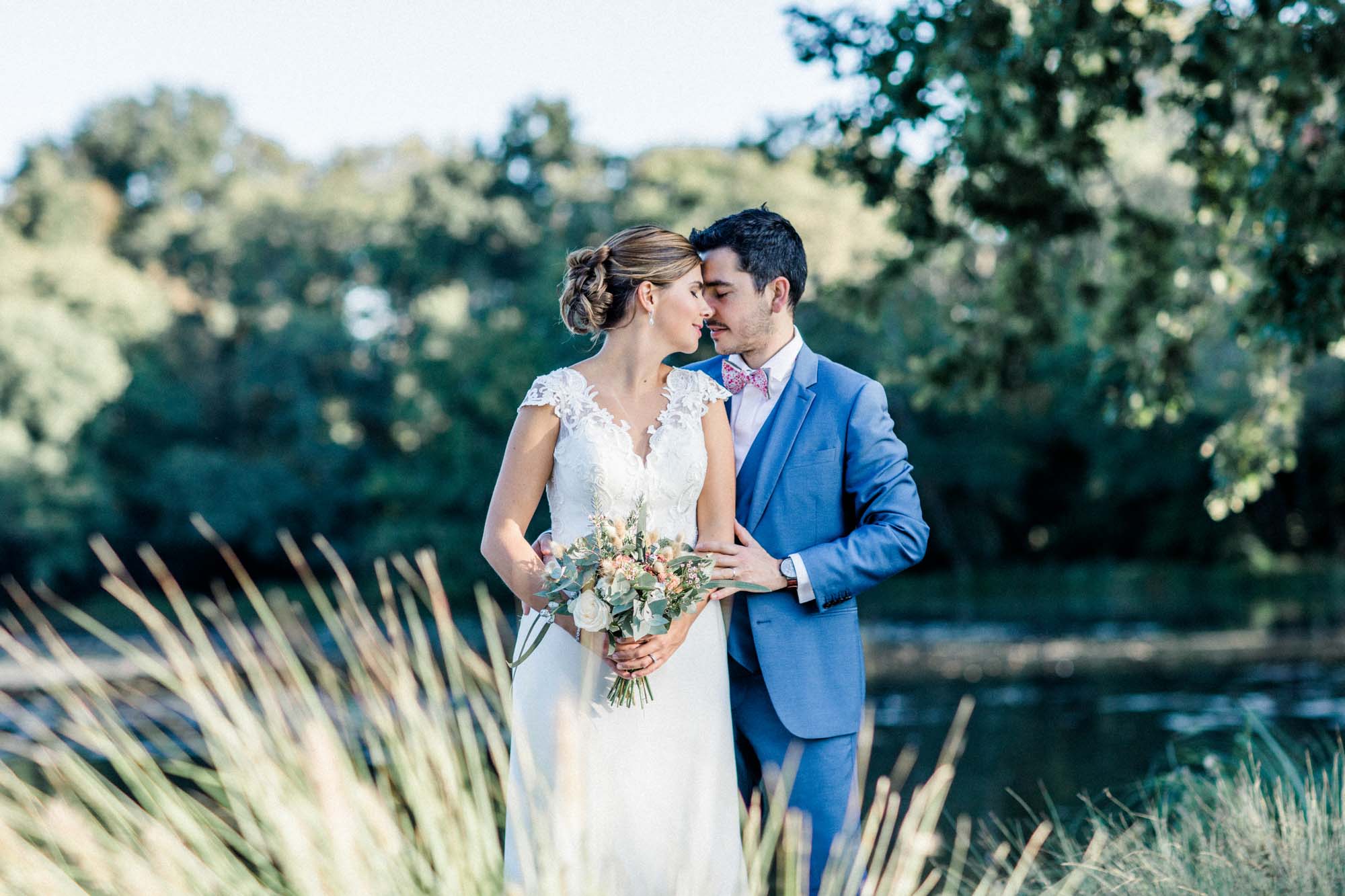 Couple embracing at the water's edge among tall grasses