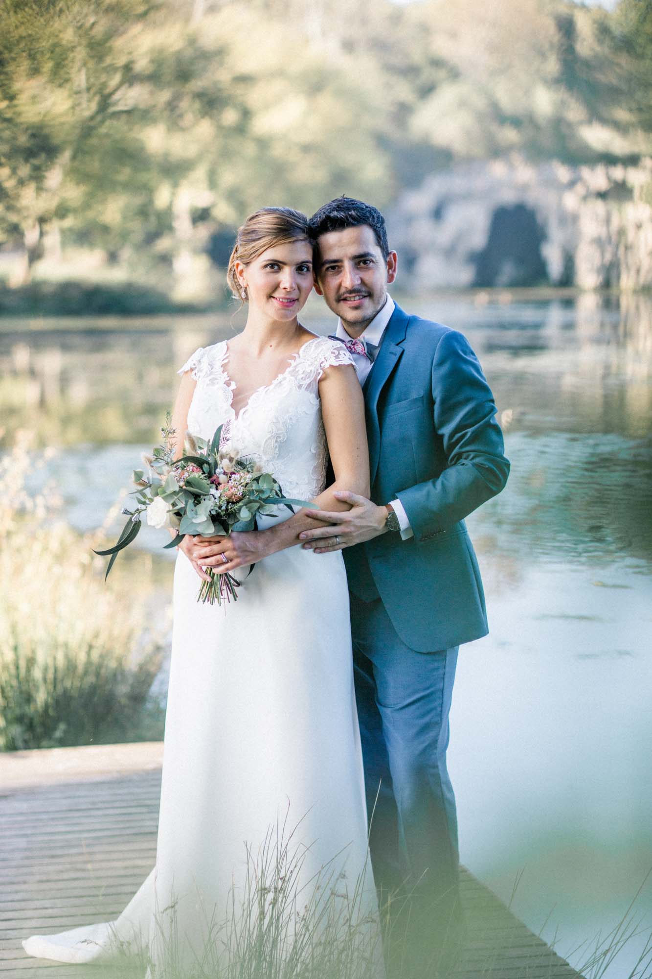 Smiling couple on a wooden jetty in front of the pond