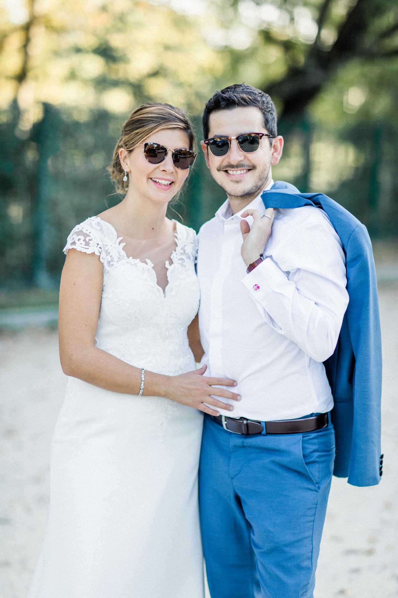 Relaxed couple in sunglasses, the groom's jacket slung over his shoulder