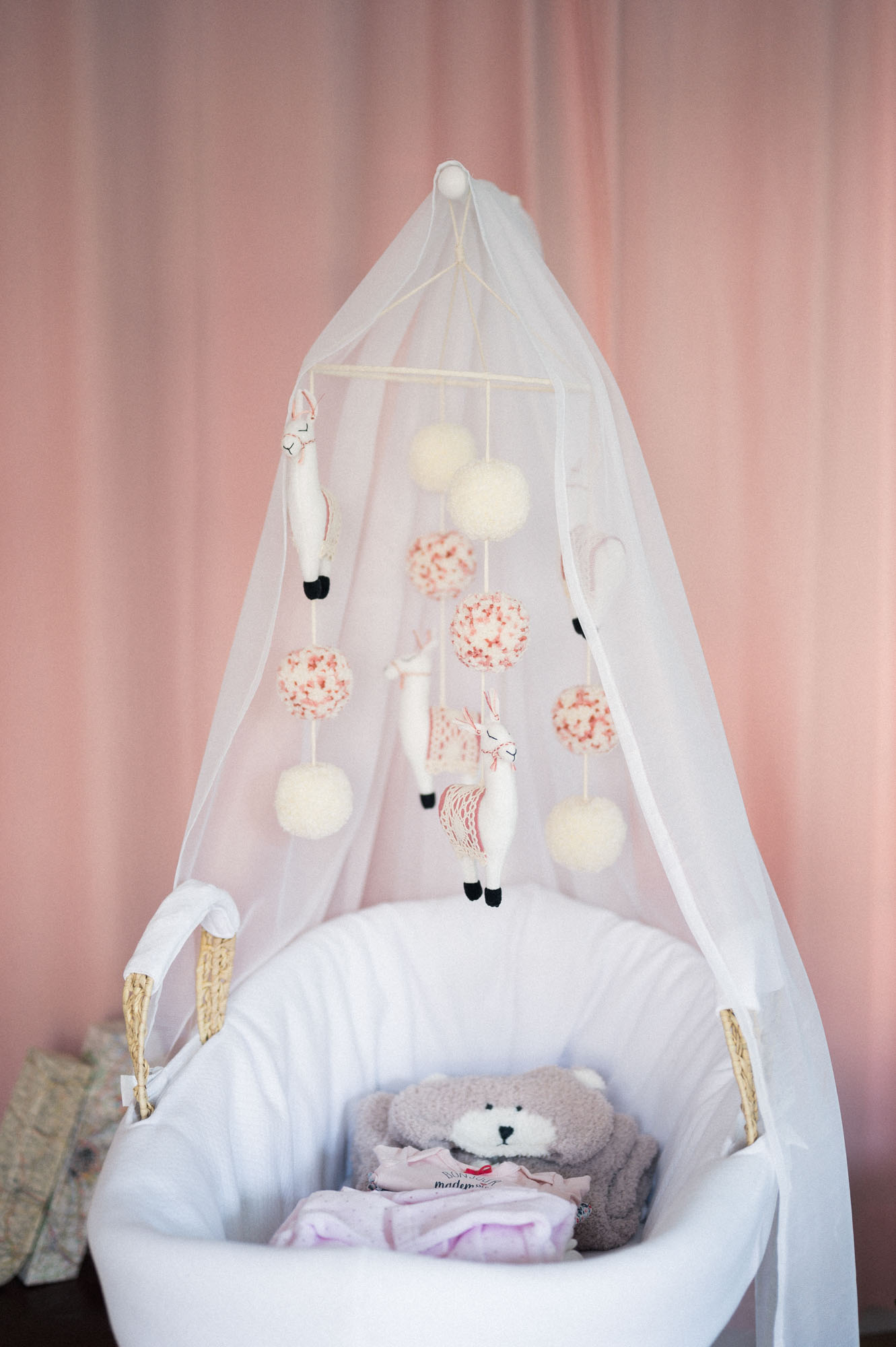 White cradle under a sheer canopy with a mobile in the nursery