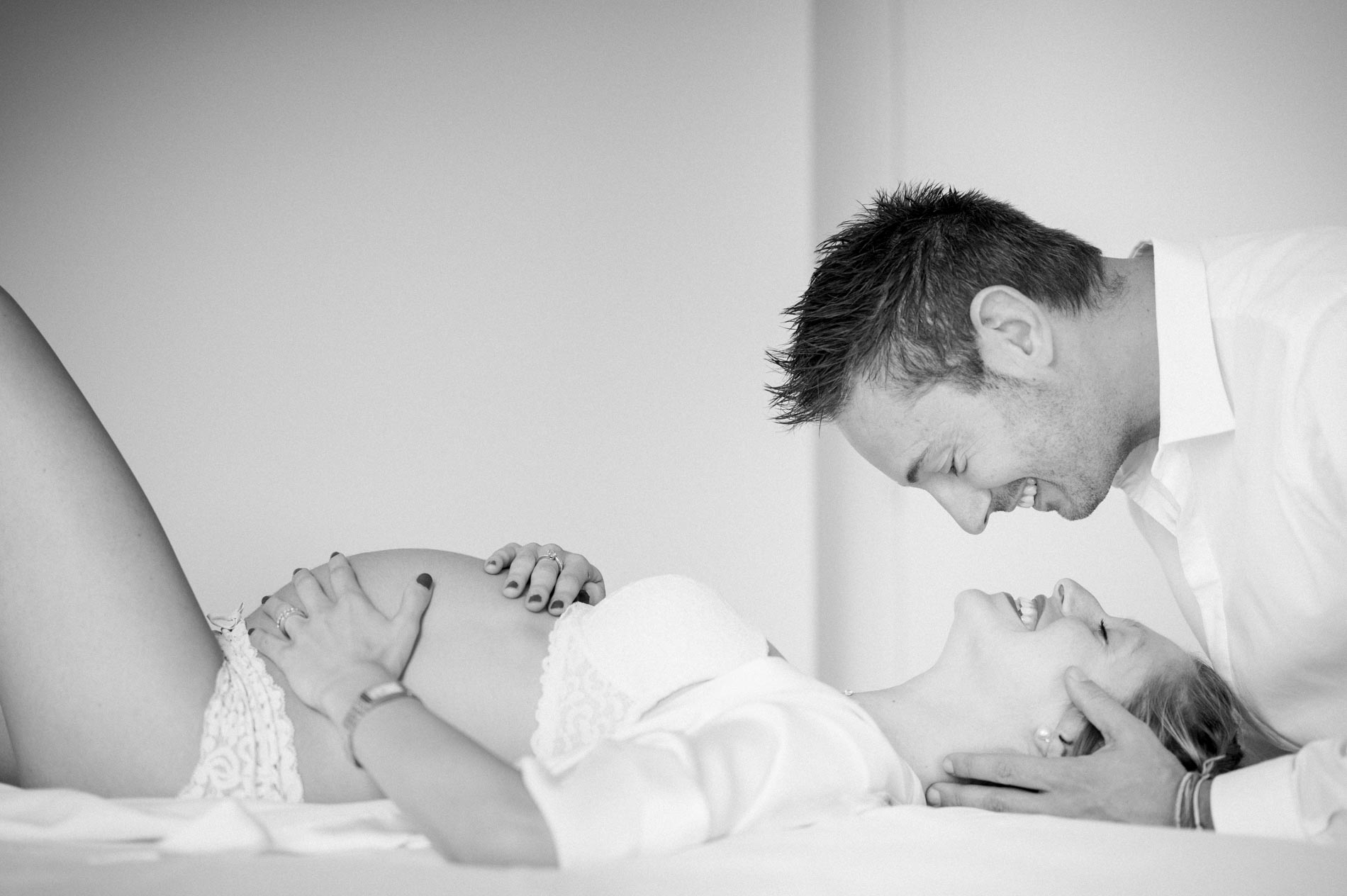 Dad-to-be leaning tenderly over the mum-to-be lying down, in black and white