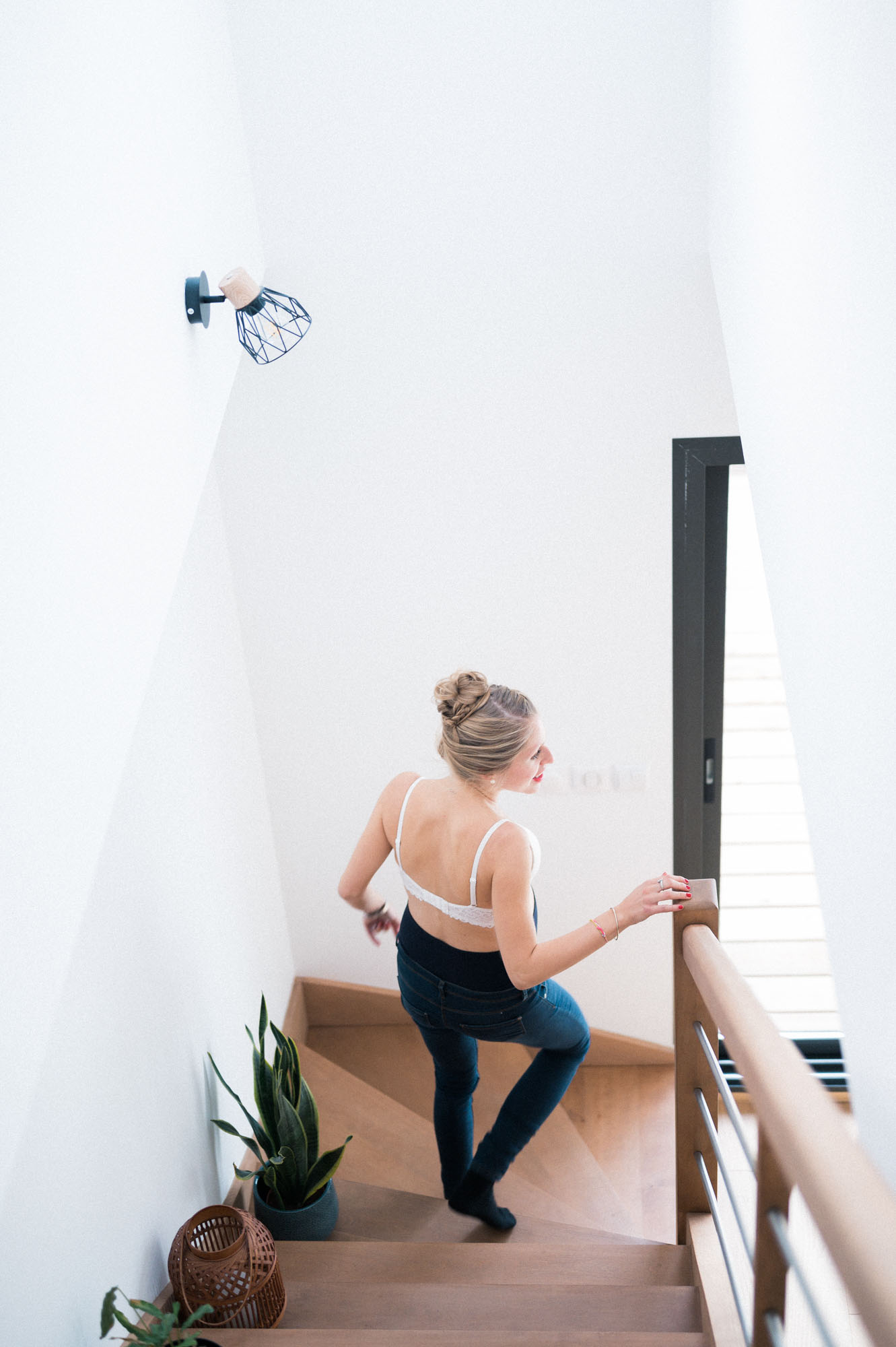 Mum-to-be walking down the stairs at home, seen from behind