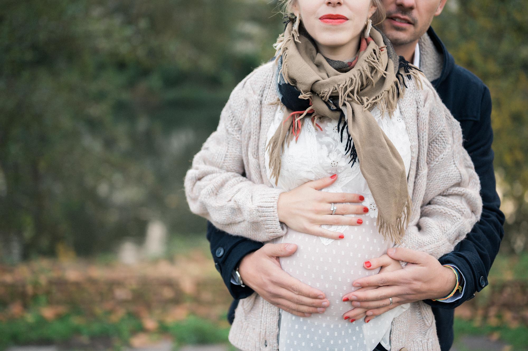 Dad-to-be wrapping his arms around the bump outdoors in autumn