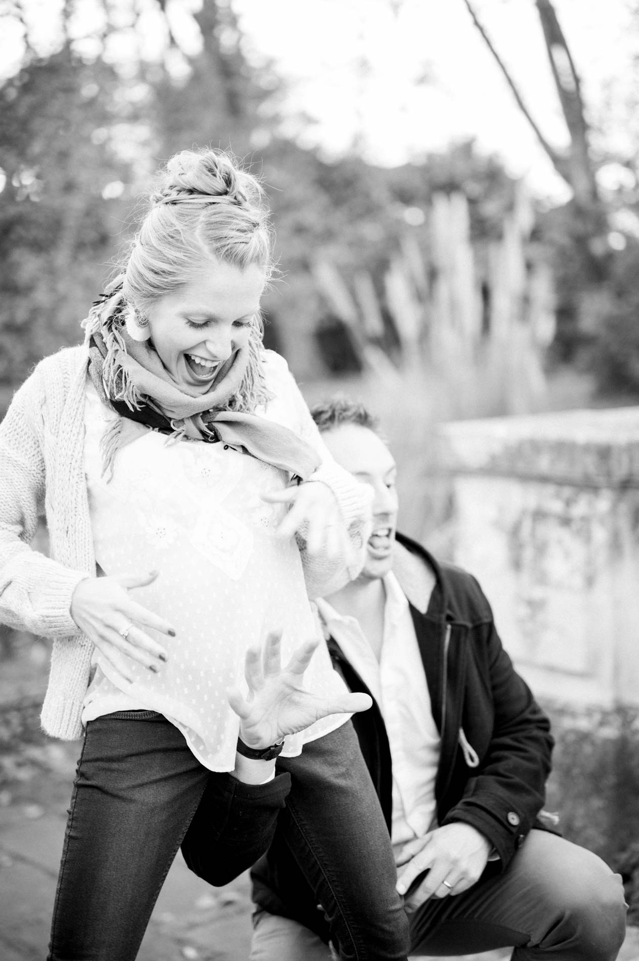 Parents-to-be laughing heartily outdoors, in black and white