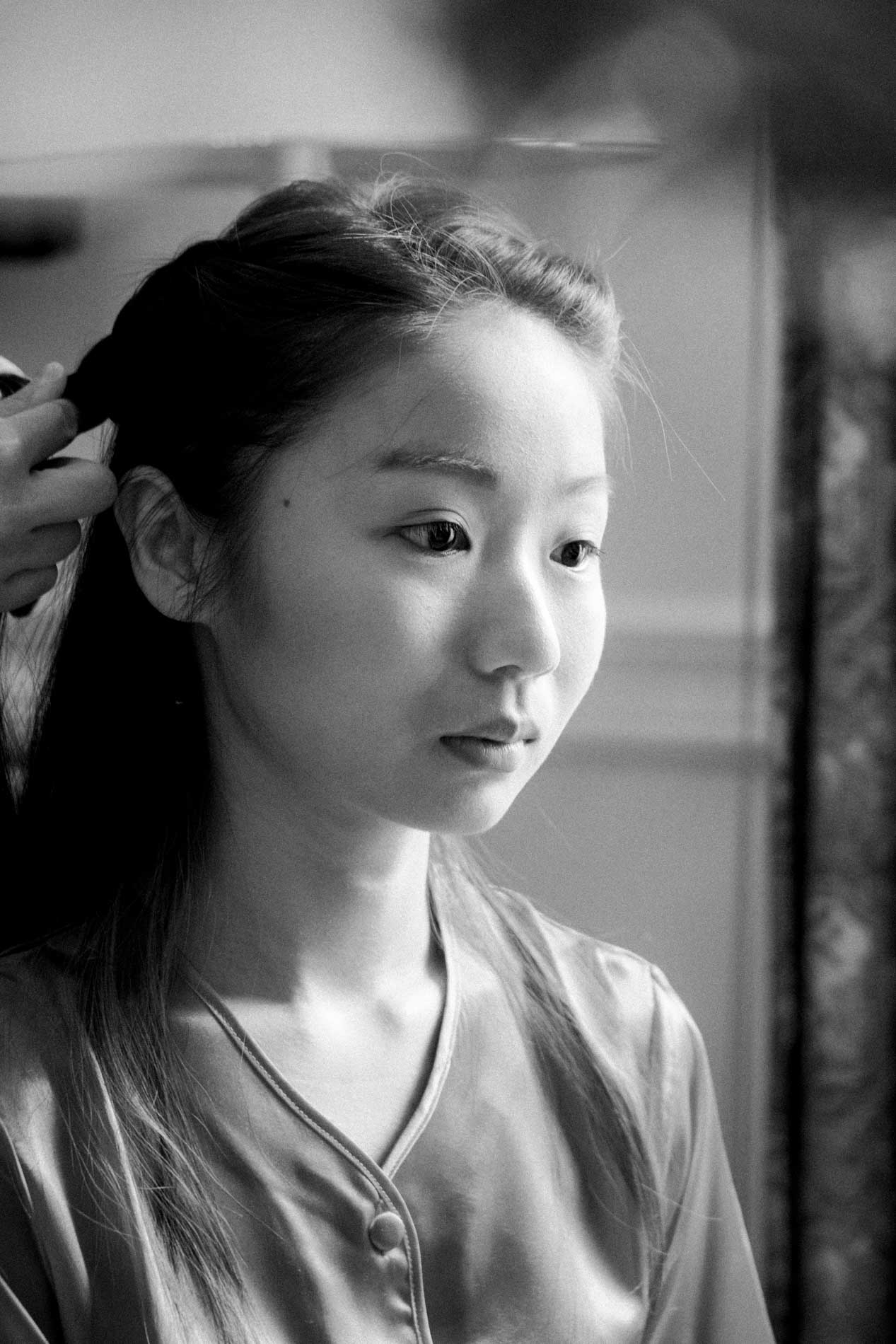 Thoughtful girl fixing her hair during the preparations, in black and white