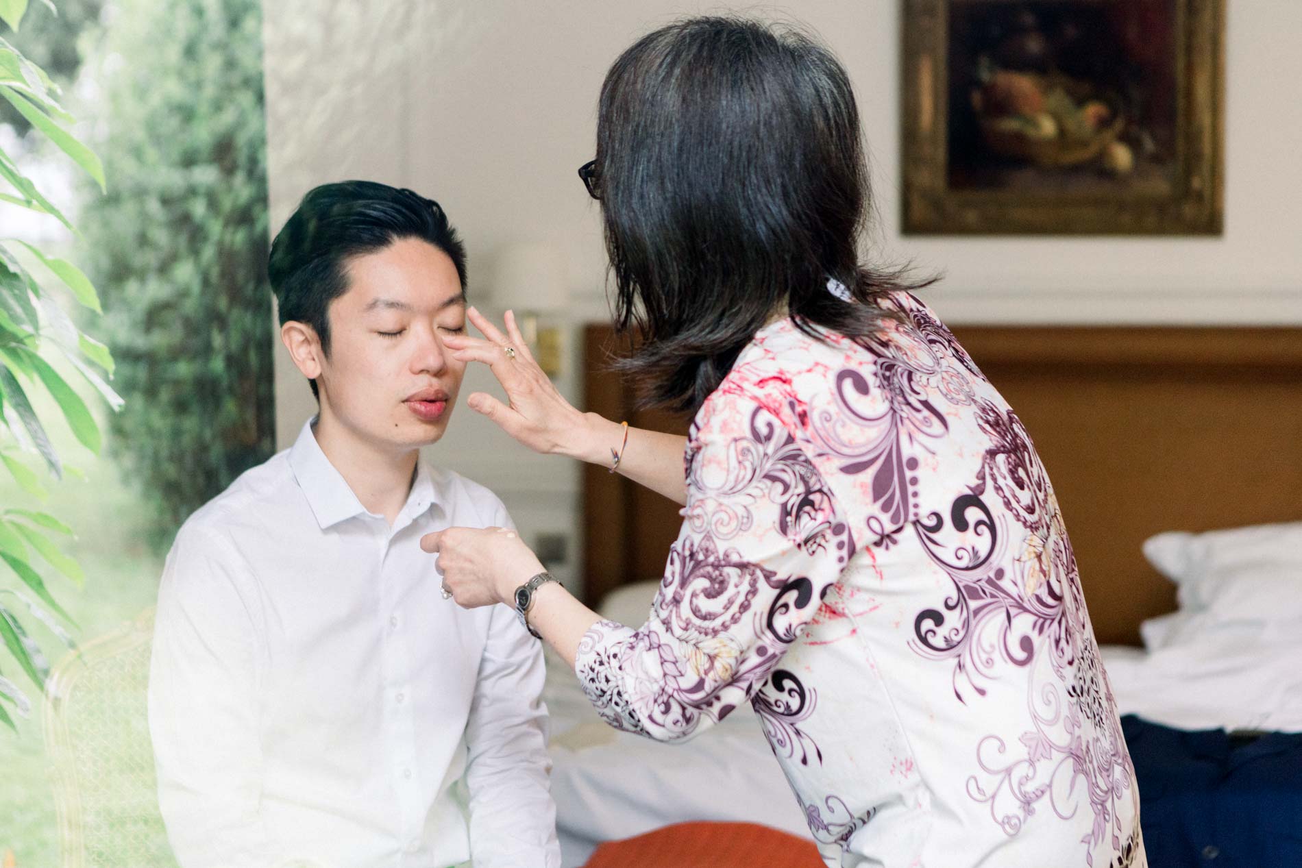 A relative adjusting the groom's collar in his room at the château