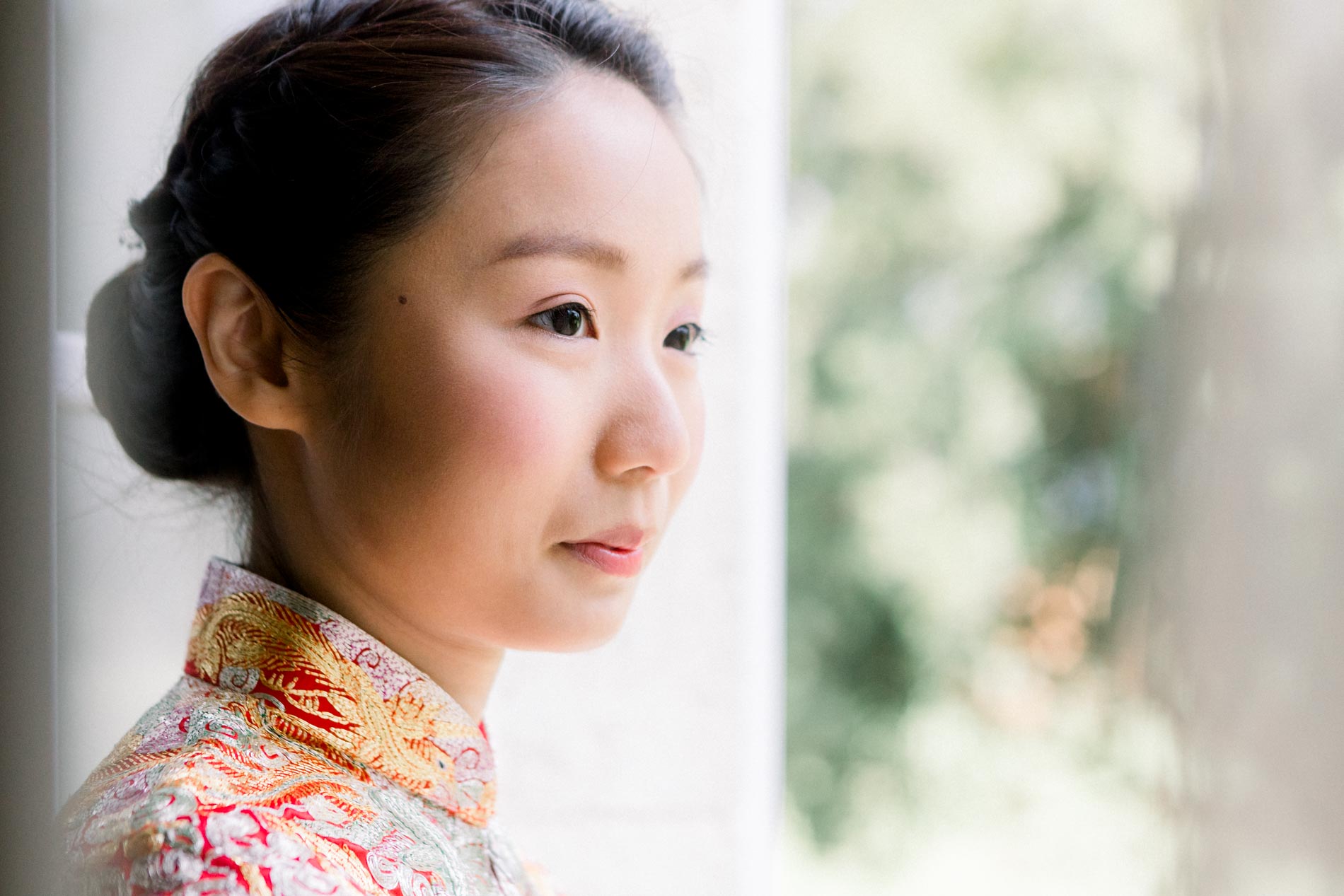 Portrait of the bride in an embroidered traditional Chinese outfit by a window