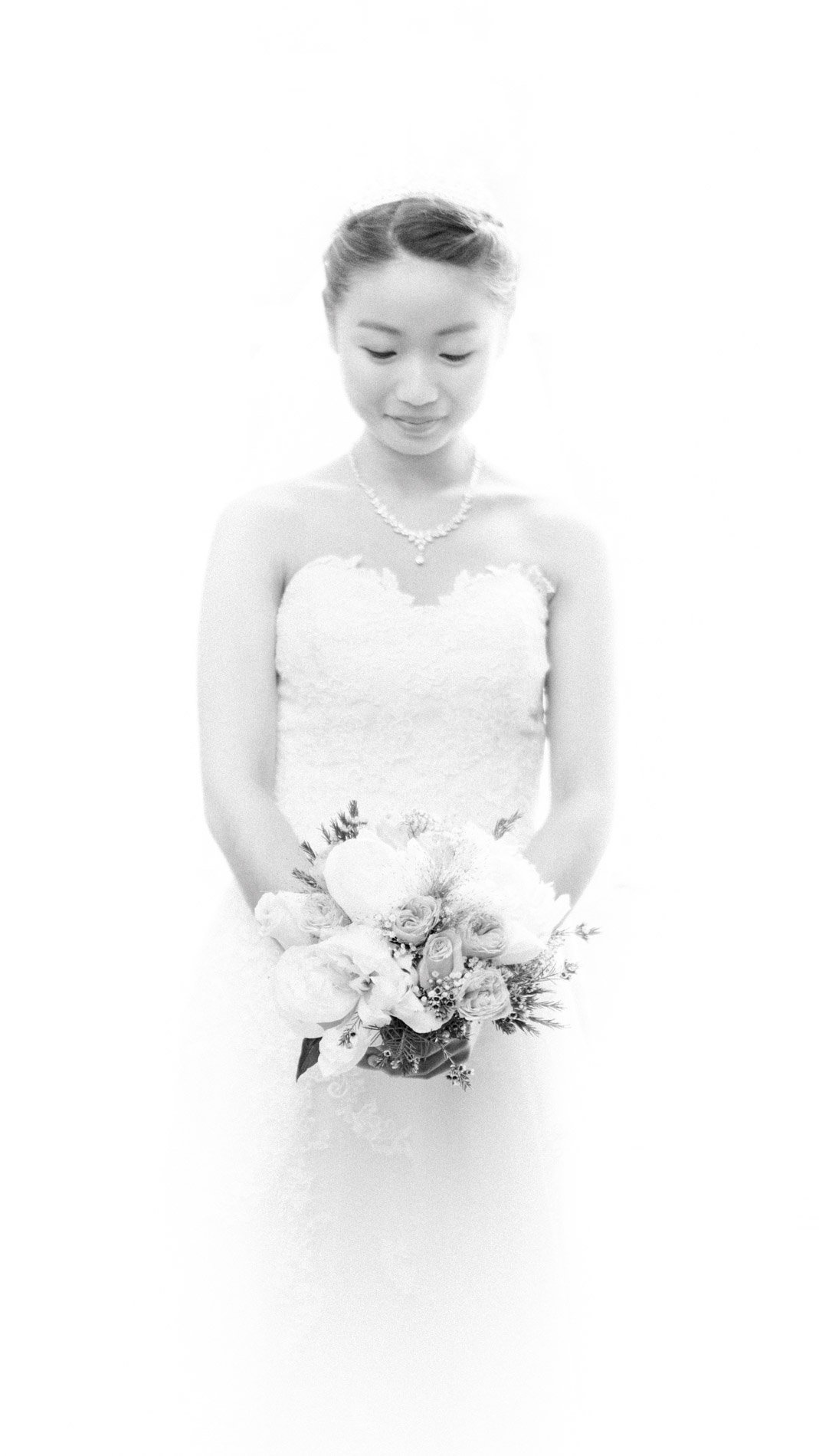 The bride in a strapless gown holding her bouquet, high-key portrait