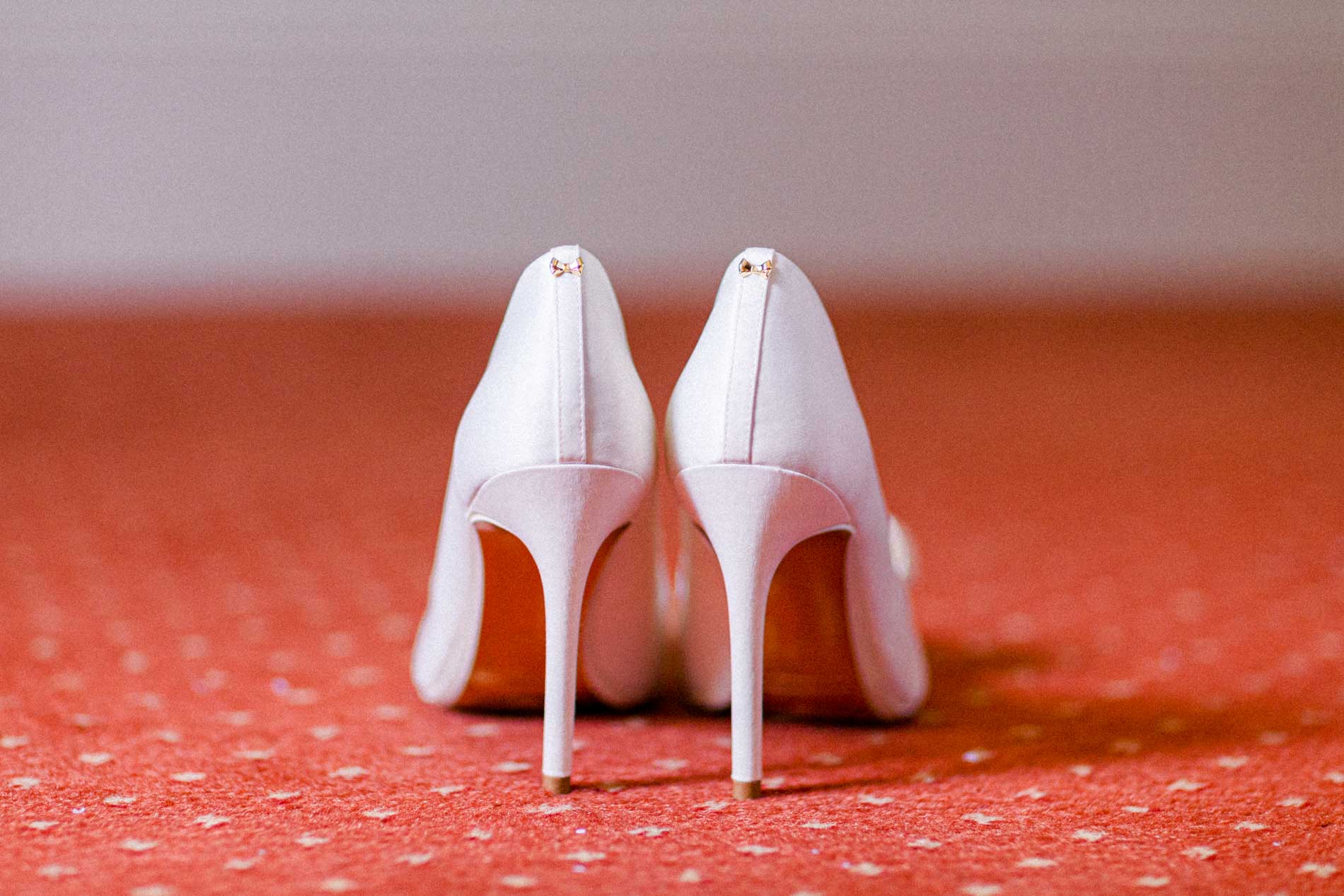 The bride's white high heels on a red carpet